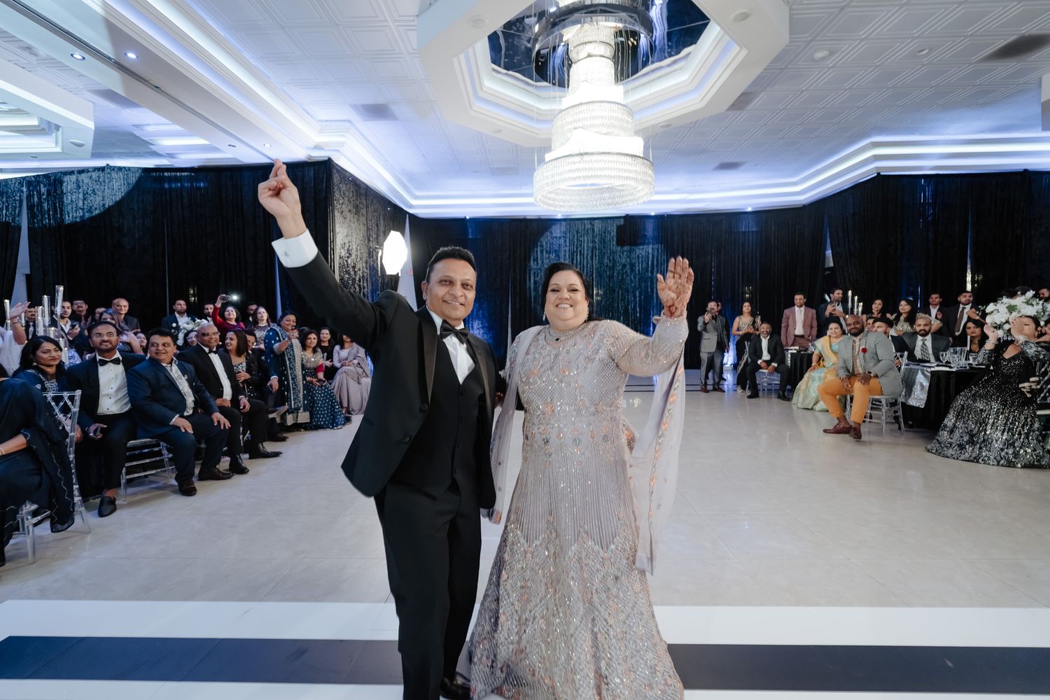 Wedding celebration in a modern venue with blue LED lighting and white decor elements.