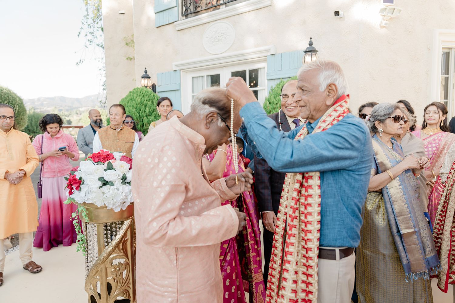 Wedding guests gathered outdoors during a celebration with traditional Indian attire and decorations.