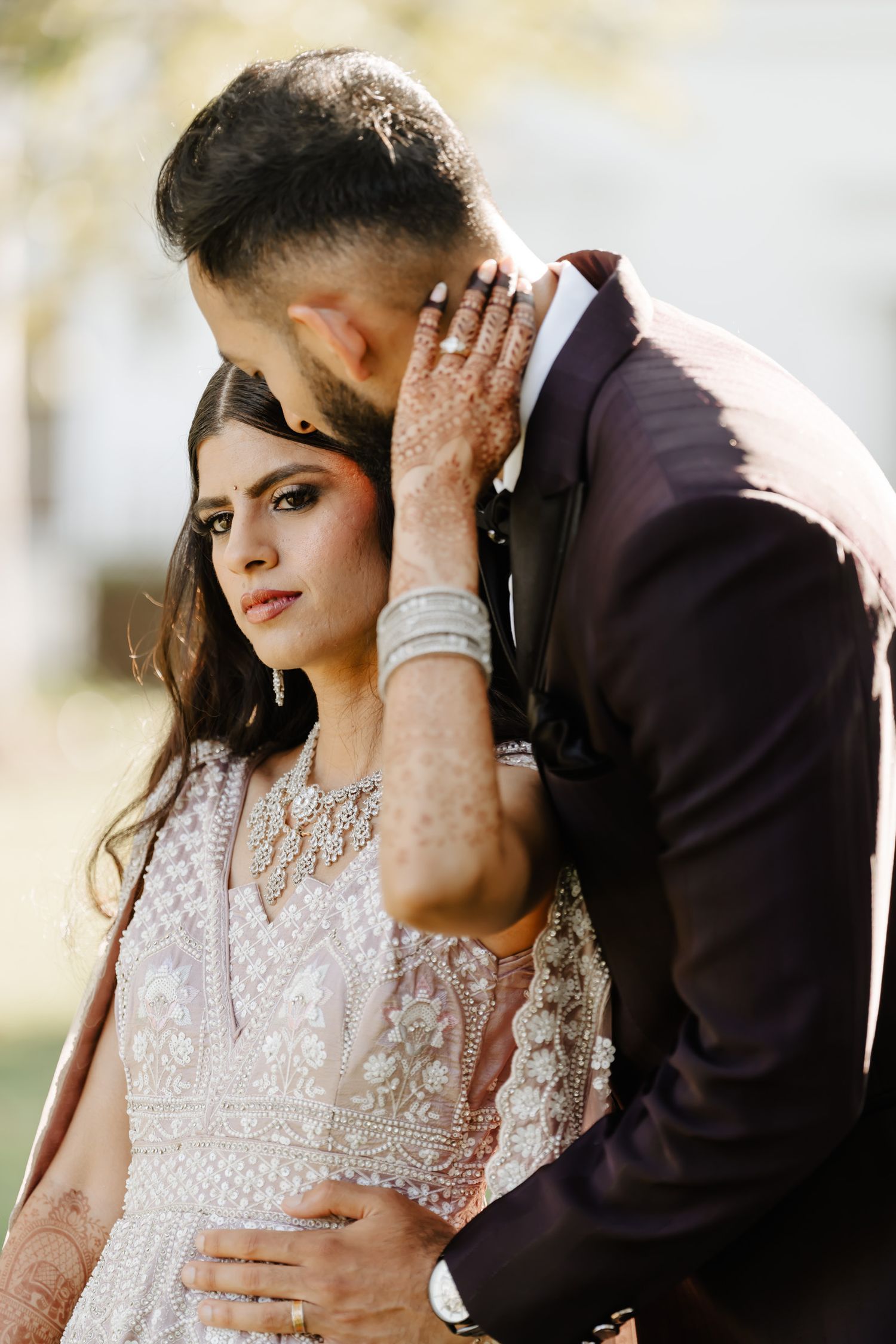 An intimate wedding portrait captured outdoors with intricate bridal details and natural lighting.