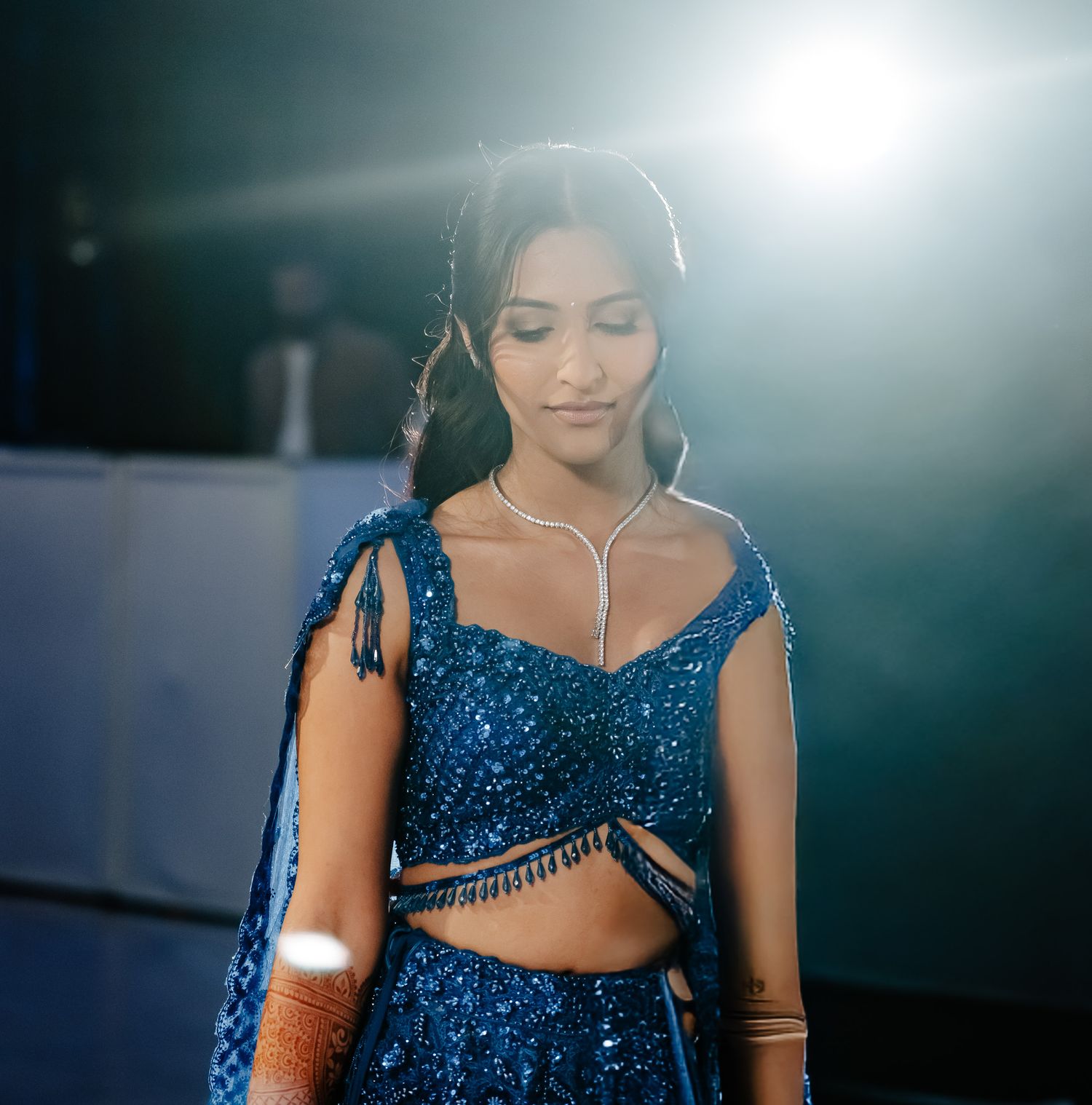 Sparkling blue sequined dress details captured in dramatic lighting at formal event.