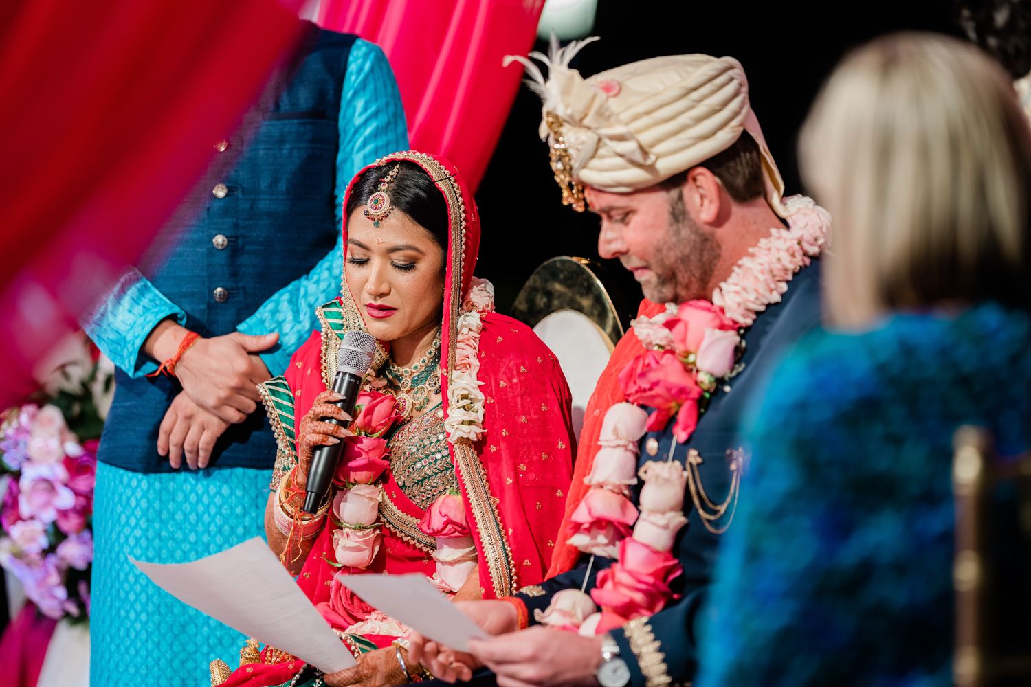 Guests celebrate at a vibrant Indian wedding ceremony with bright red and turquoise decor.