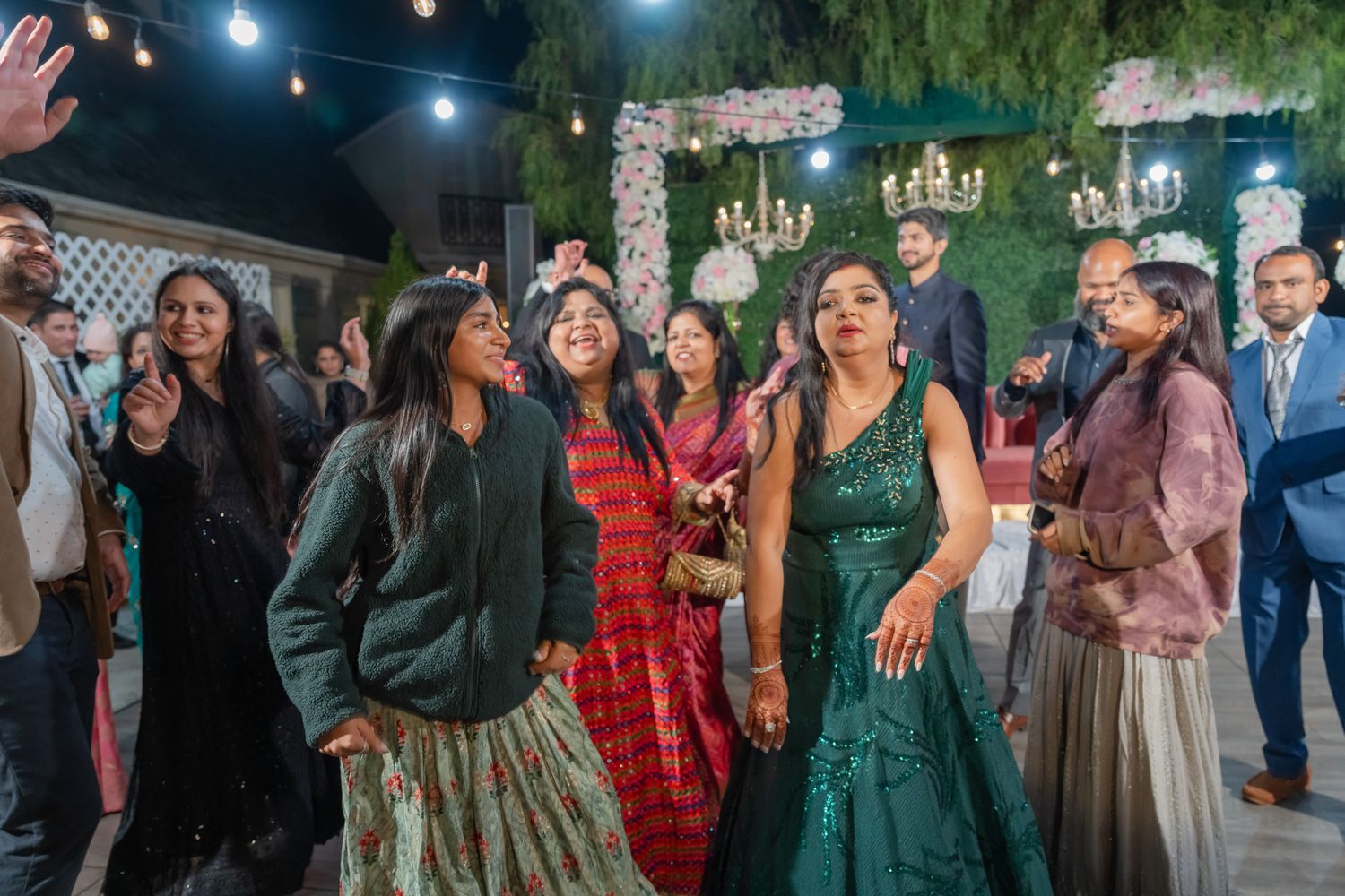 Wedding reception guests dance and celebrate on an outdoor dance floor during evening festivities.