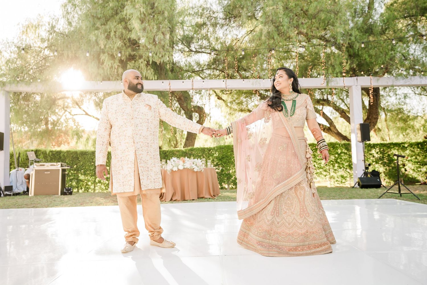 A couple walks through a beautiful outdoor garden setting during a wedding celebration.