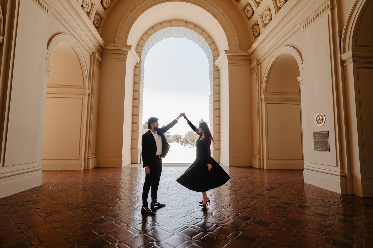 Couple dancing under a grand arch in a classic building with stunning architectural details.