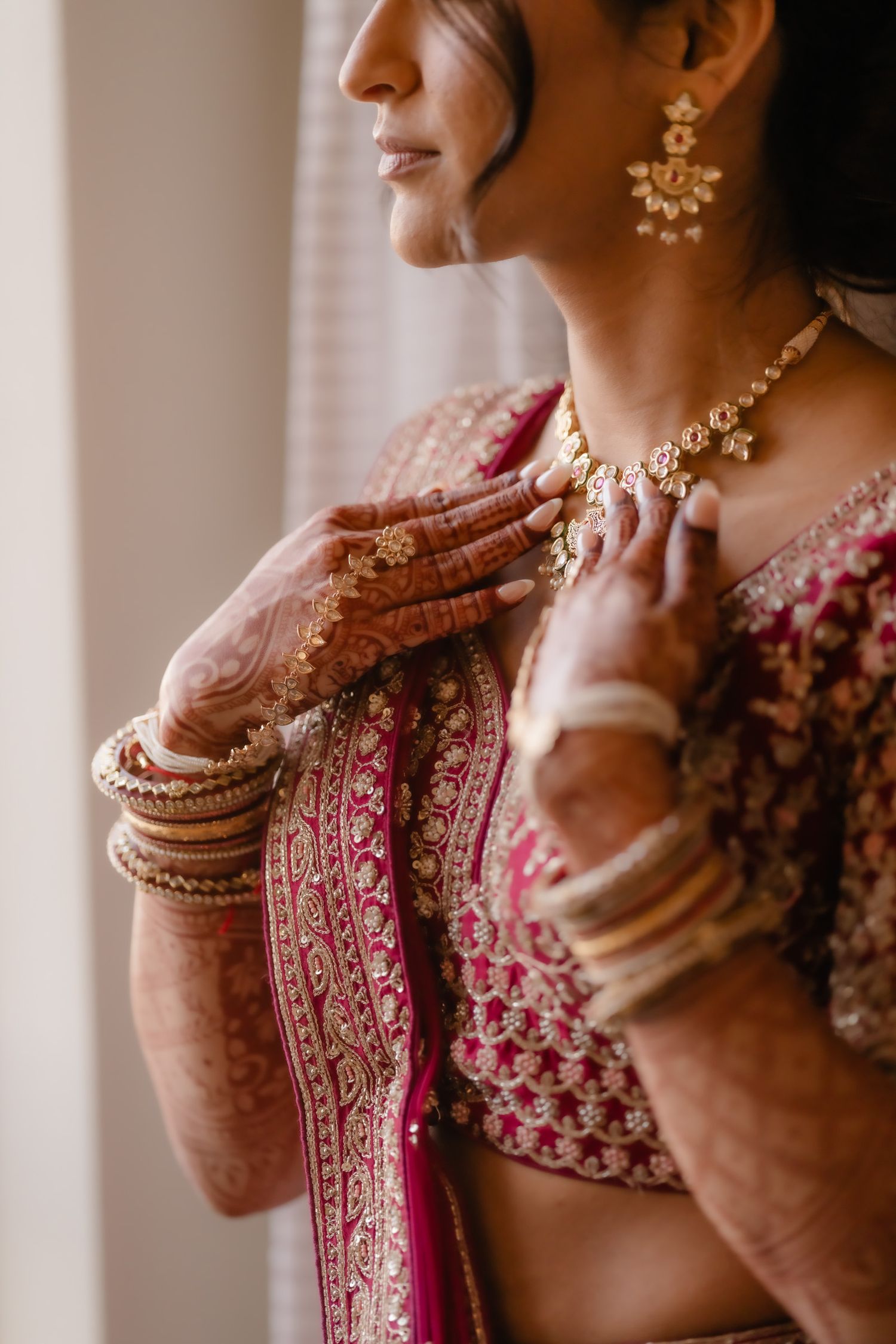 Close-up details of bridal jewelry and henna-adorned hands with traditional Indian wedding attire.