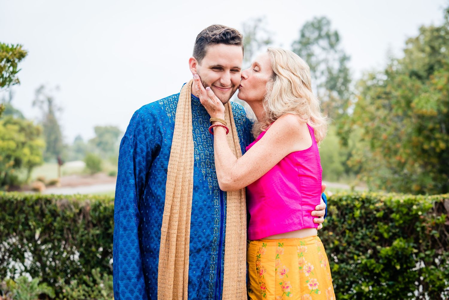 A romantic moment between two people in colorful fusion outfits against a garden backdrop.