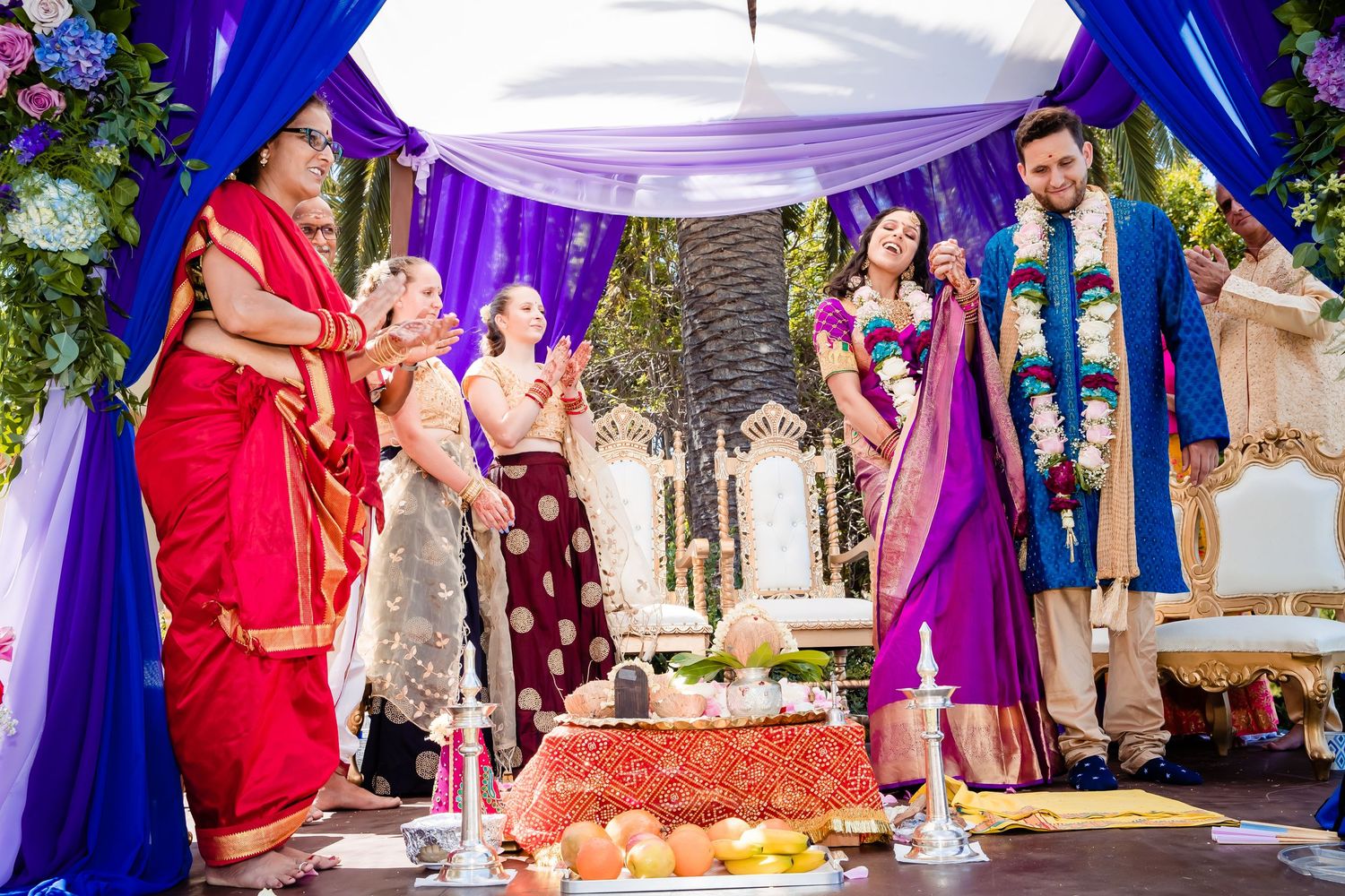 Wedding celebration featuring vibrant purple and red attire during an outdoor ceremony with decorative lighting.