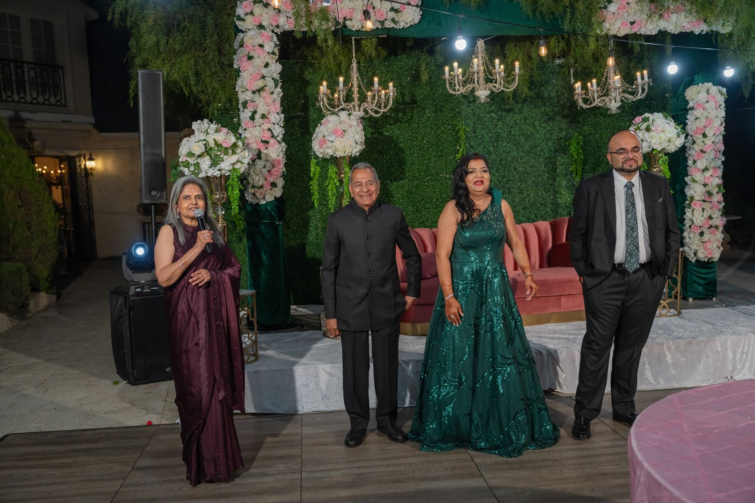 Elegant event space decorated with chandeliers and floral arrangements features guests mingling at a formal celebration.