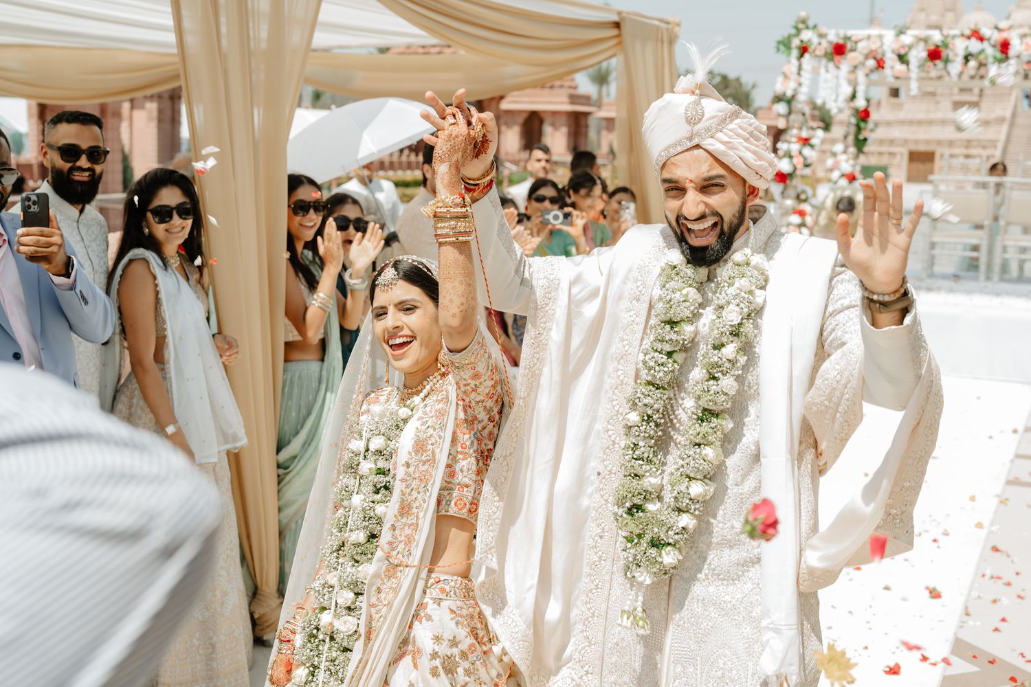 Outdoor wedding celebration with white drapes and floral decorations at a luxurious venue.