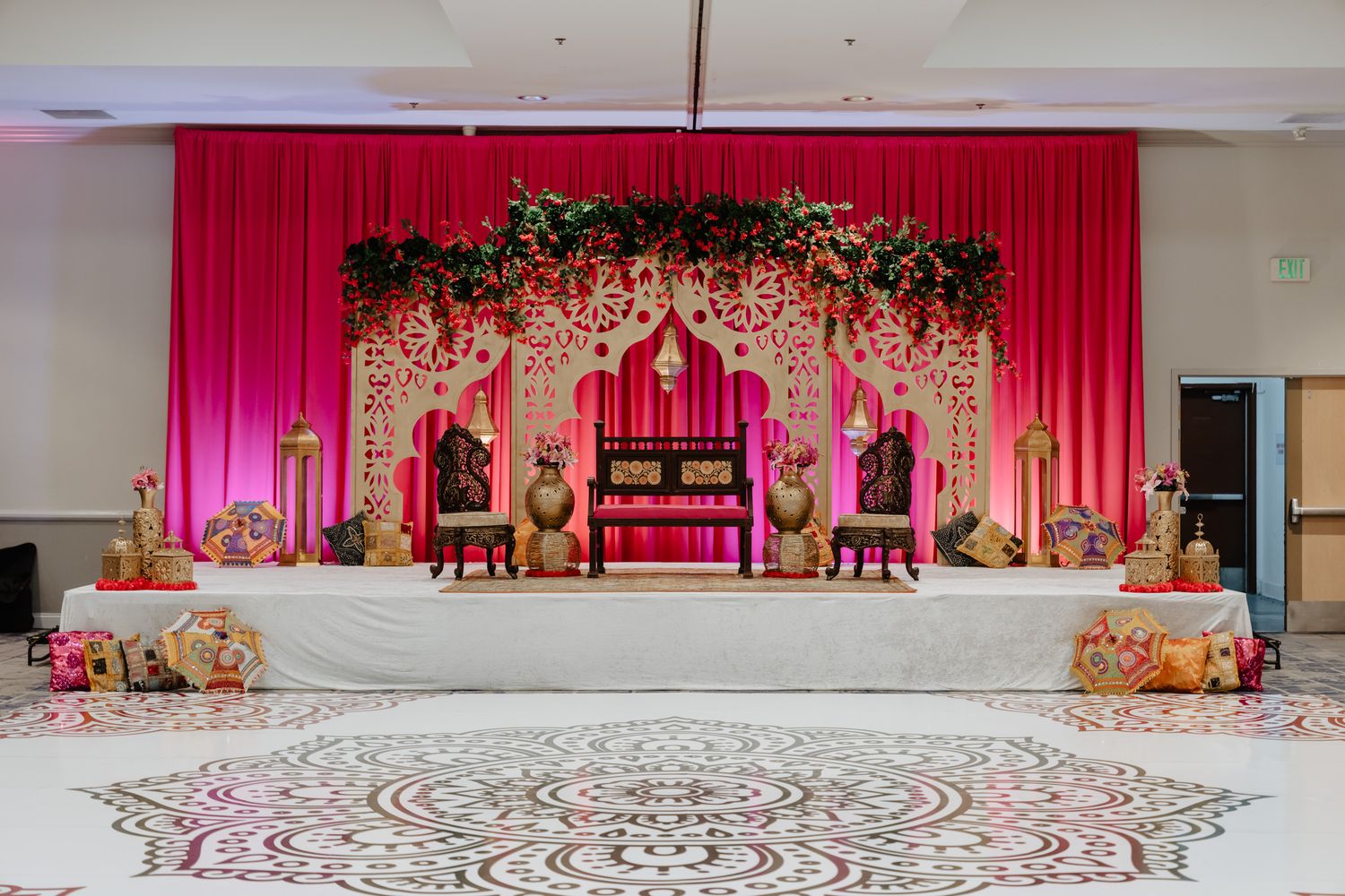 Wedding stage decorations in pink and gold with floral arrangements and elegant drapes for an Indian ceremony.