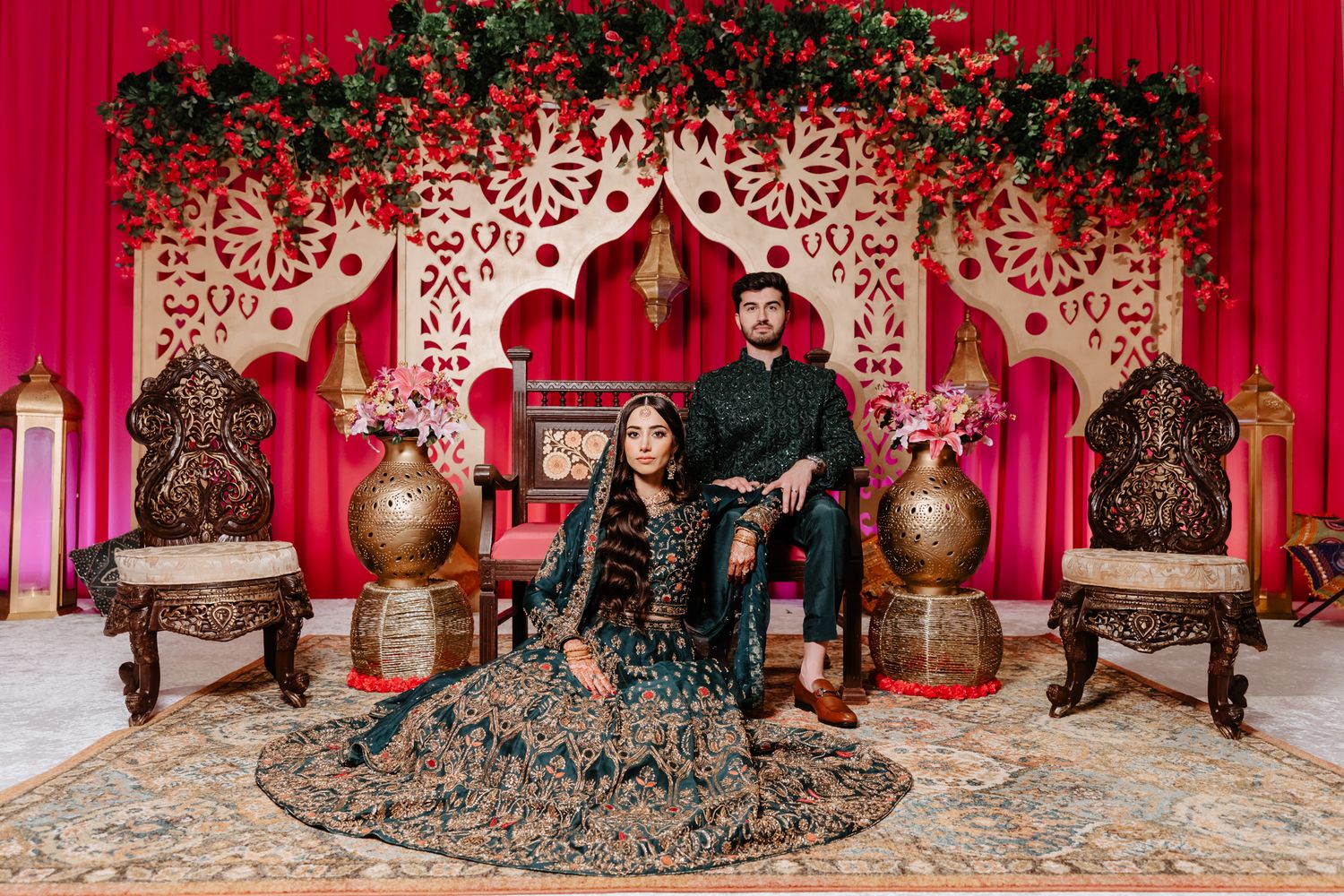 A festive red and gold decorated Indian wedding stage with traditional decor elements and ornate seating arrangements.