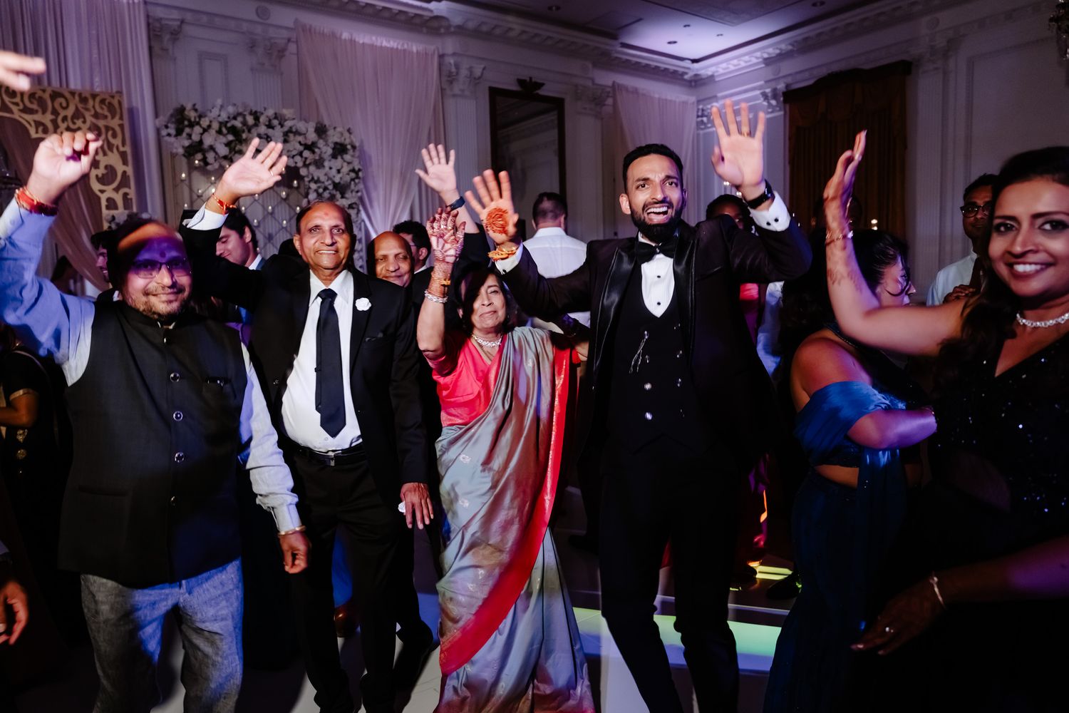 Wedding reception dance floor filled with guests celebrating with raised hands.