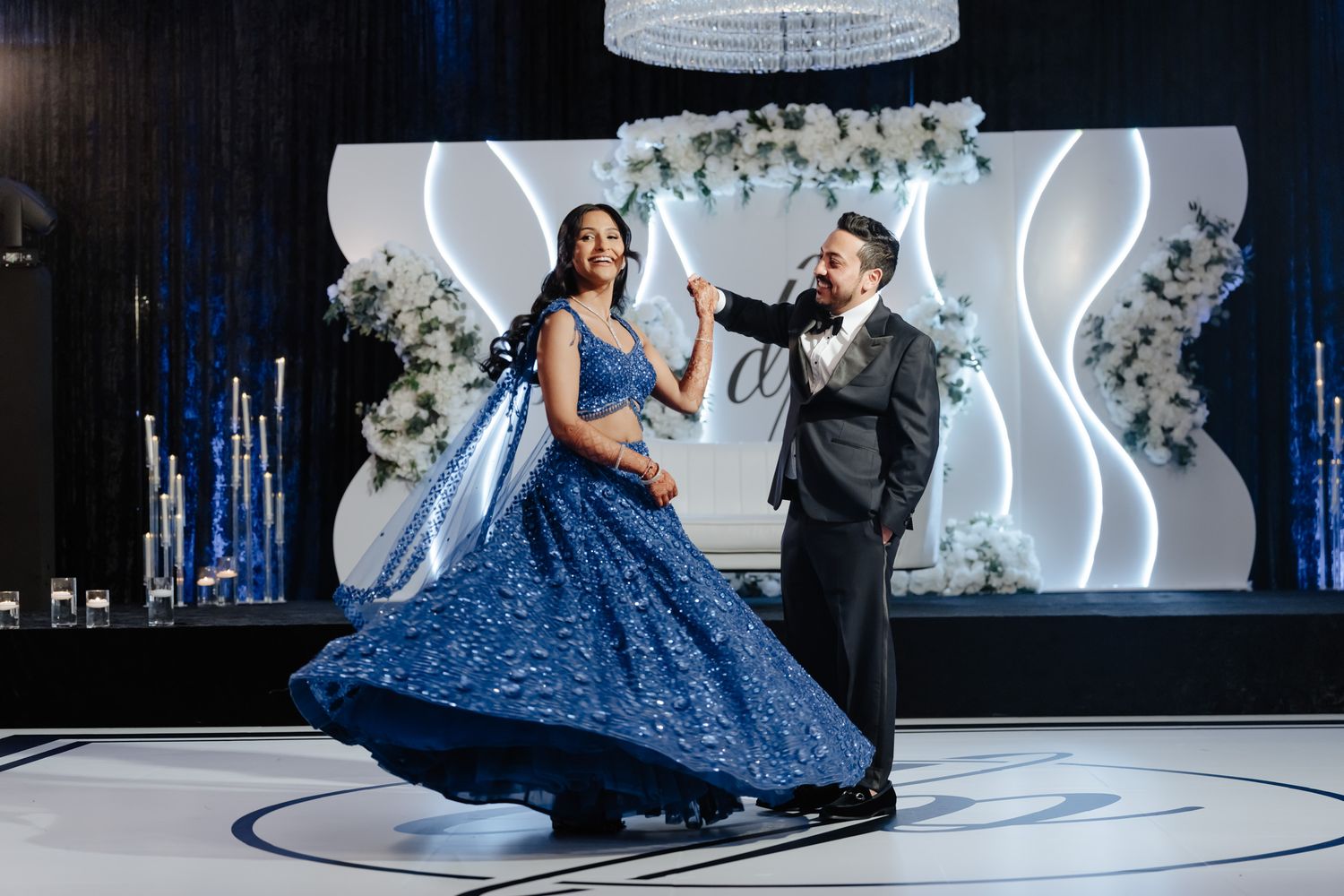 Elegant dance sequence on illuminated floor with flowing blue gown and formal attire.