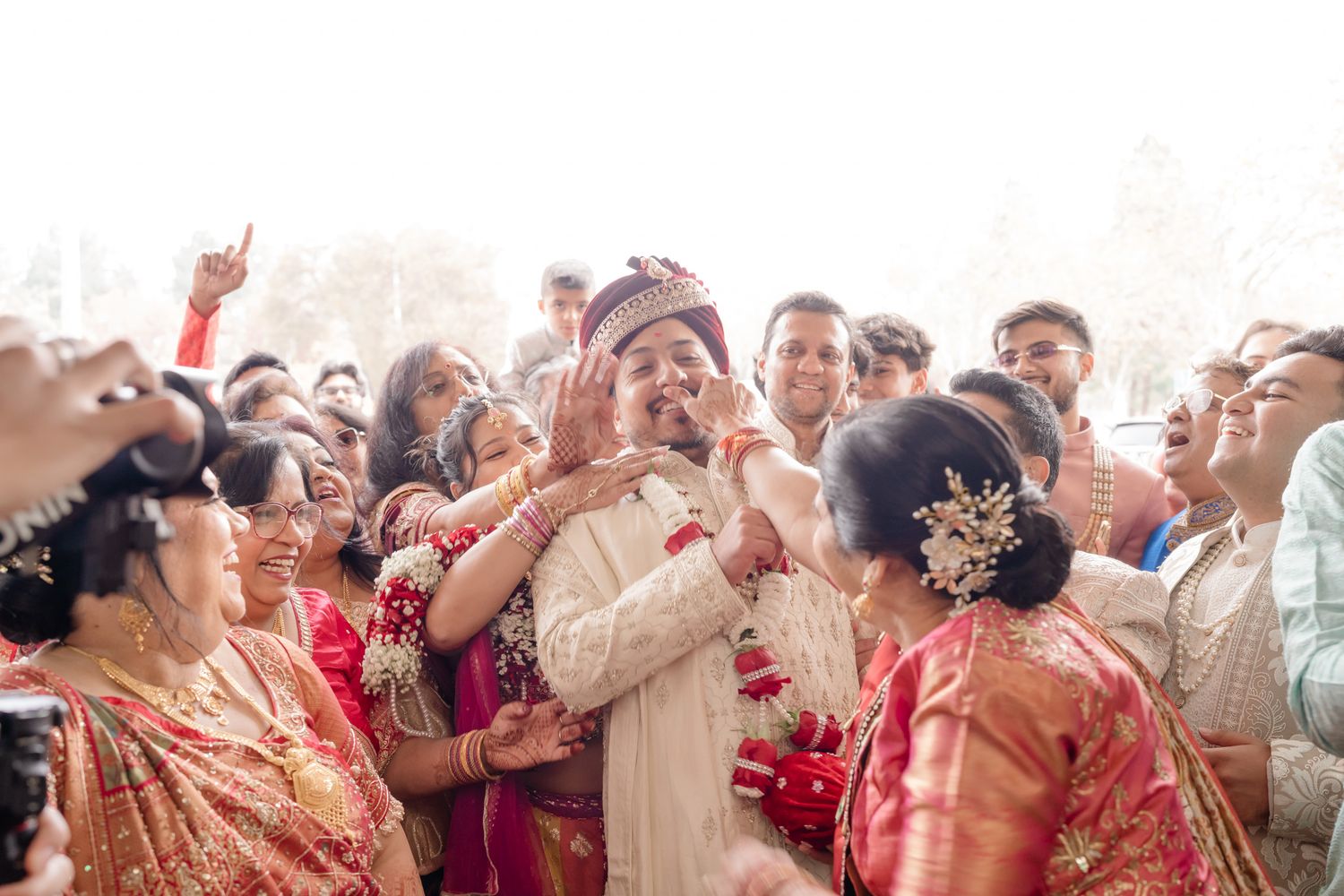 A joyous crowd celebrates at an Indian wedding ceremony with bright traditional outfits and festive energy.