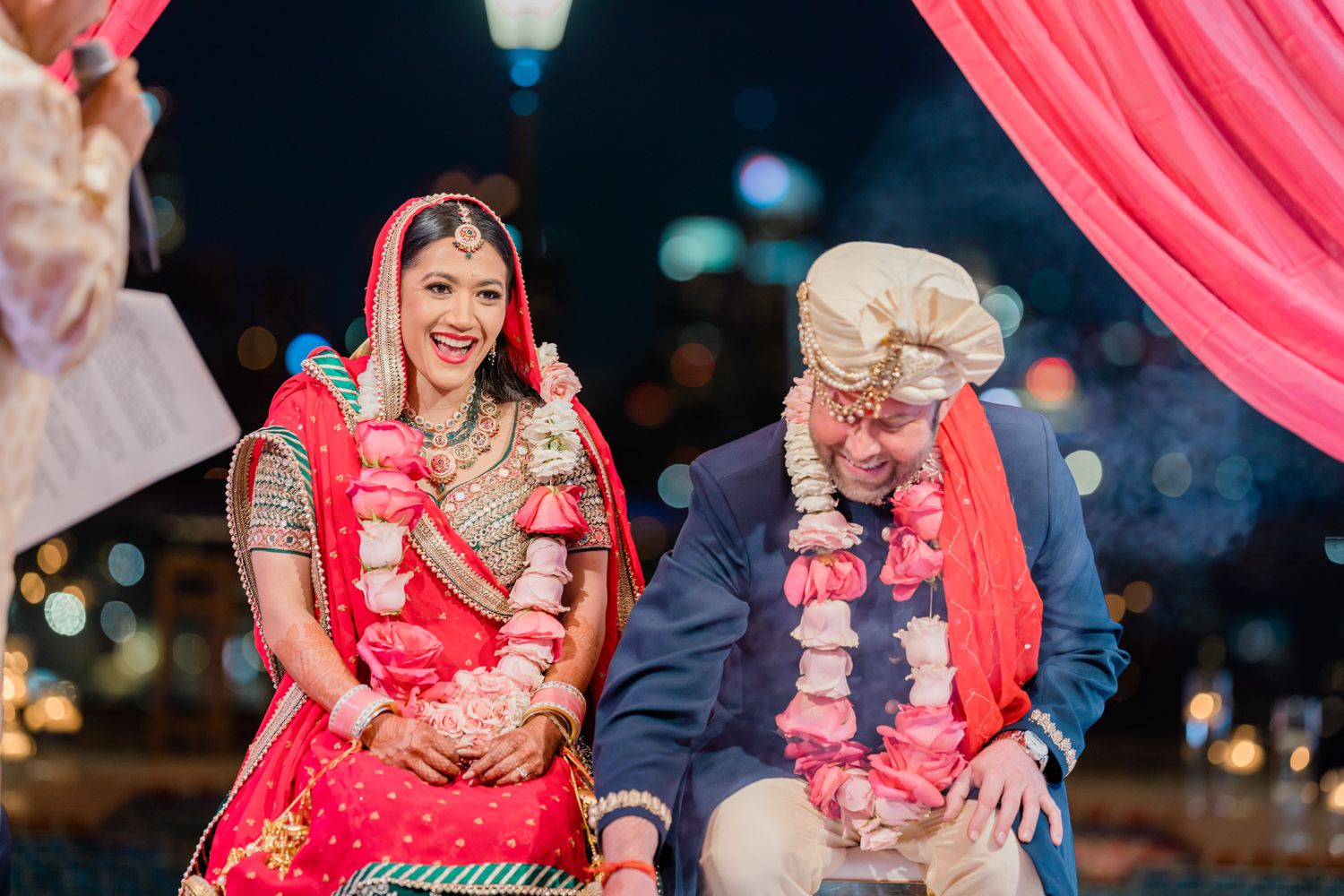 Wedding ceremony moments captured under bright pink drapes and decorative lighting.