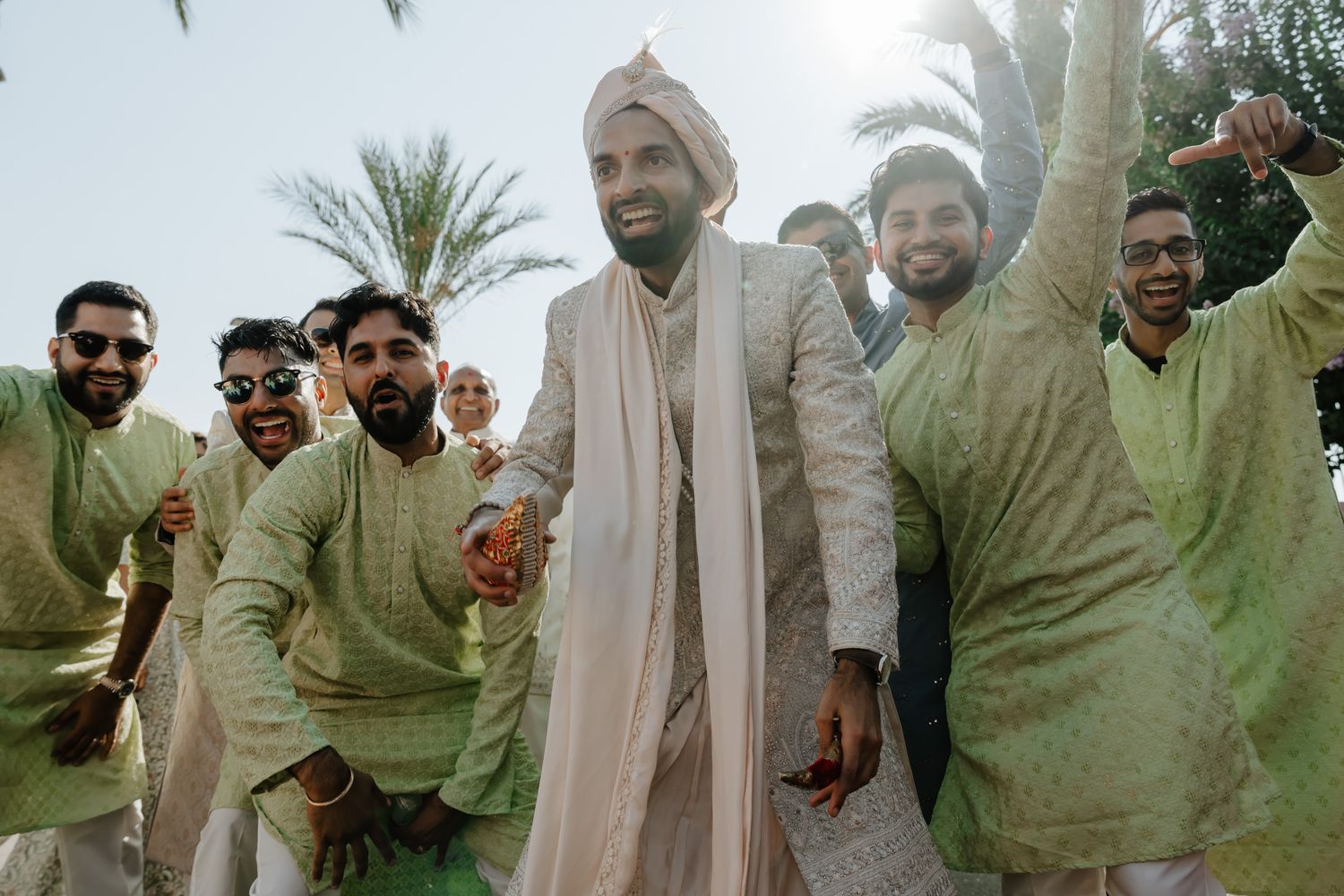 Group celebration at a traditional Indian wedding with guests in light-colored attire.