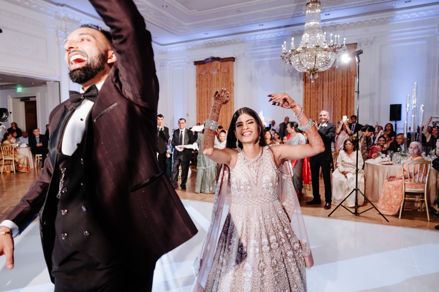 Wedding reception dance party with guests celebrating in an ornate ballroom.