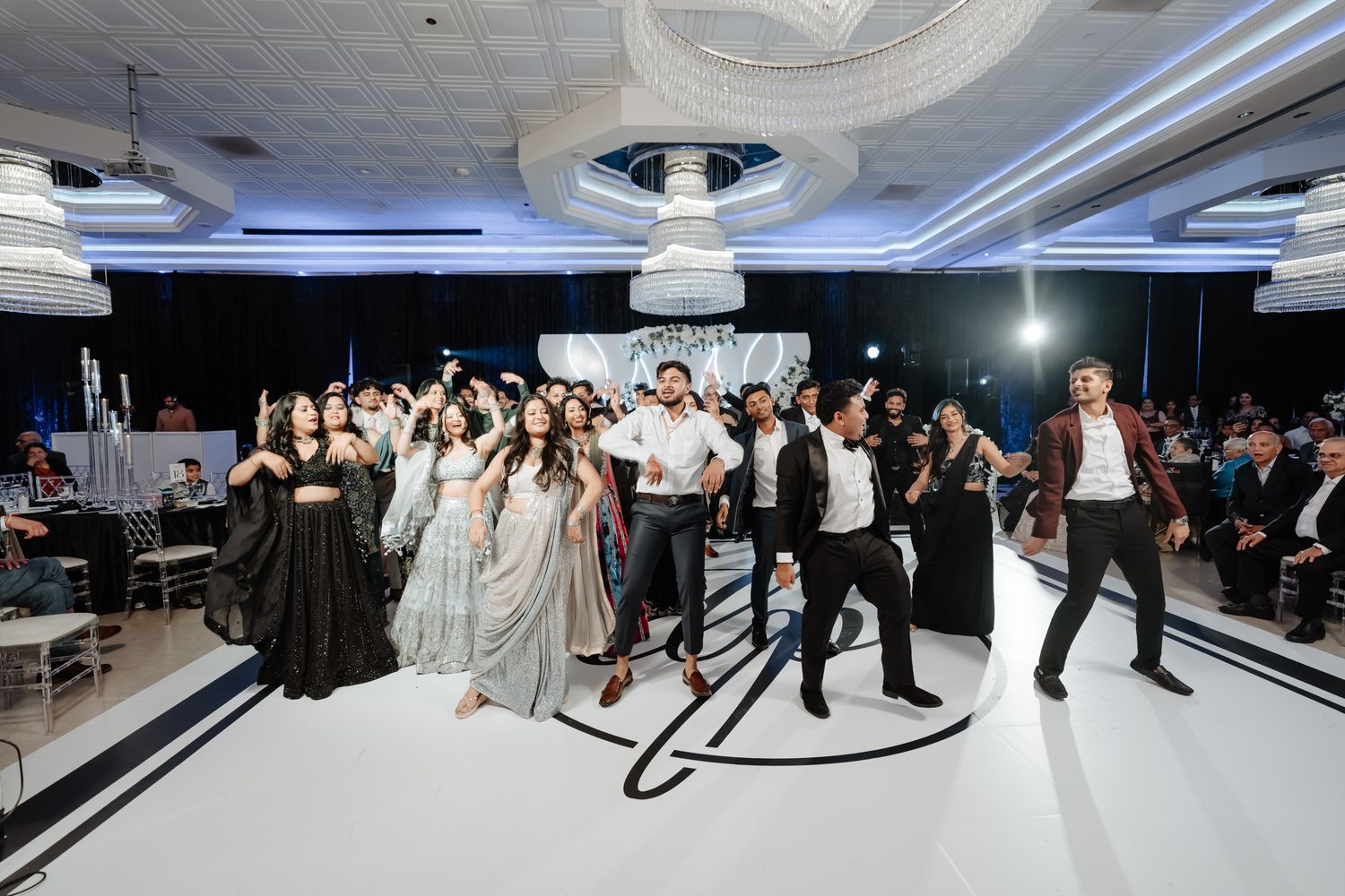 Wide panoramic view of a modern event space with white dance floor and dramatic lighting setup.