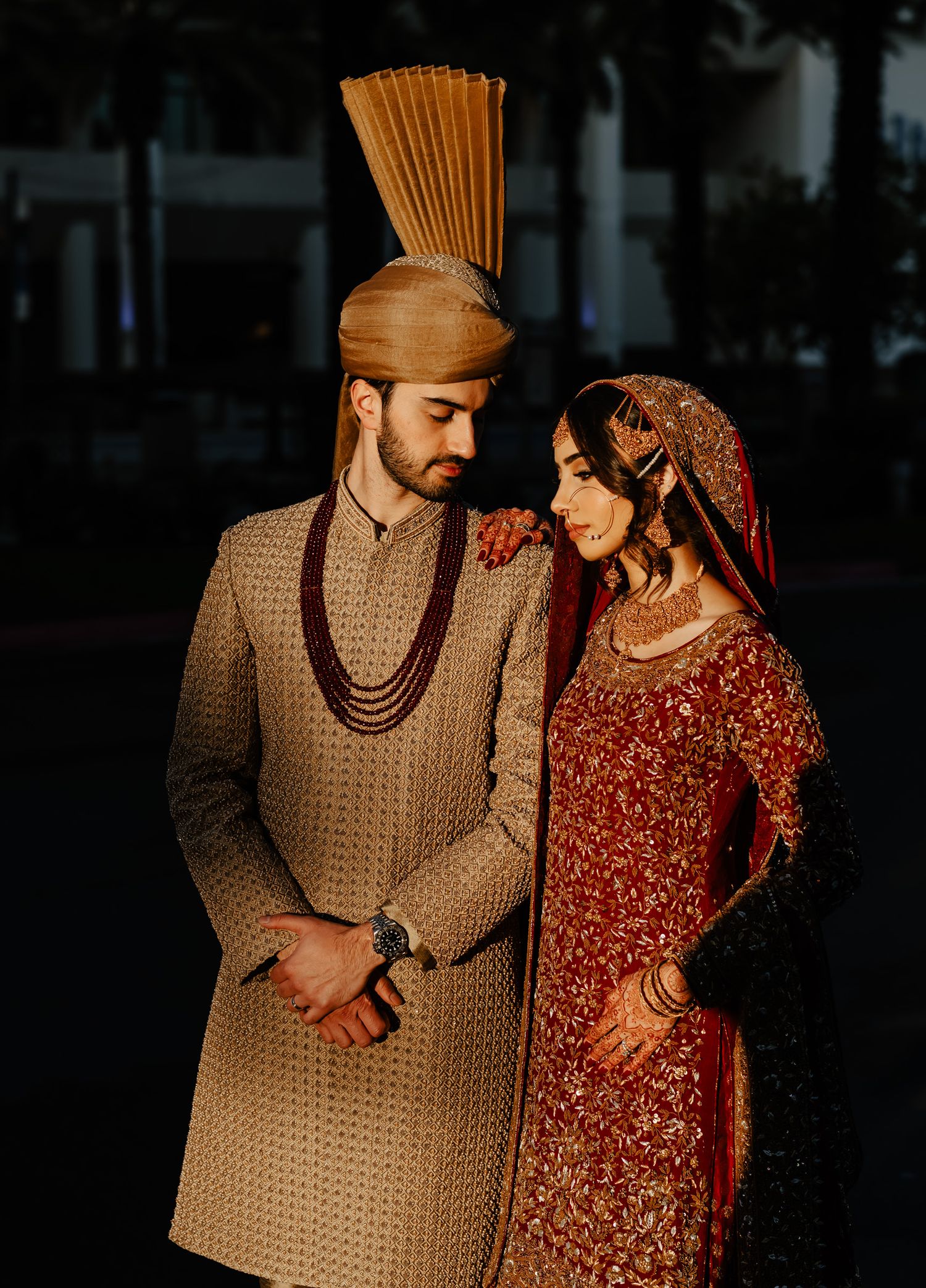A couple in traditional South Asian wedding attire poses together in a series of romantic low-light portraits.