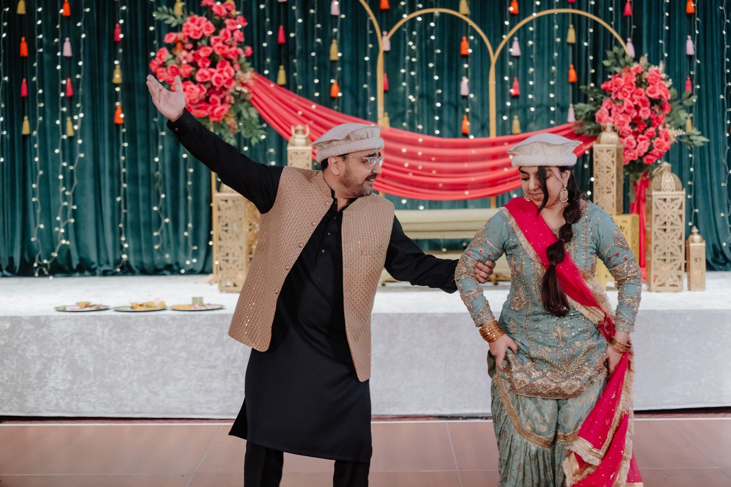 Wedding guests holding a red and white decorative cloth during a traditional South Asian wedding ceremony.