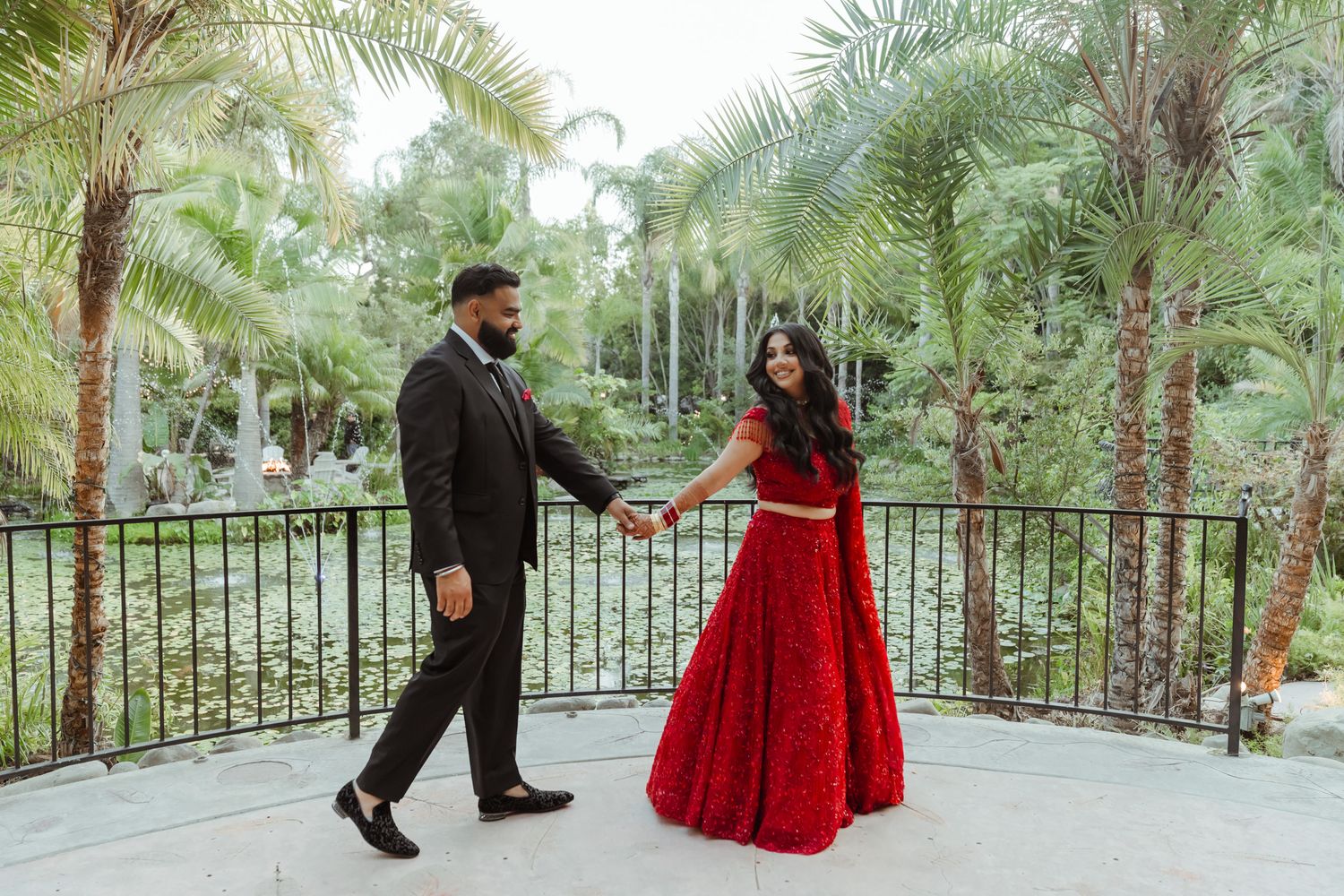 Outdoor wedding photography scene with palm trees and garden pathway.