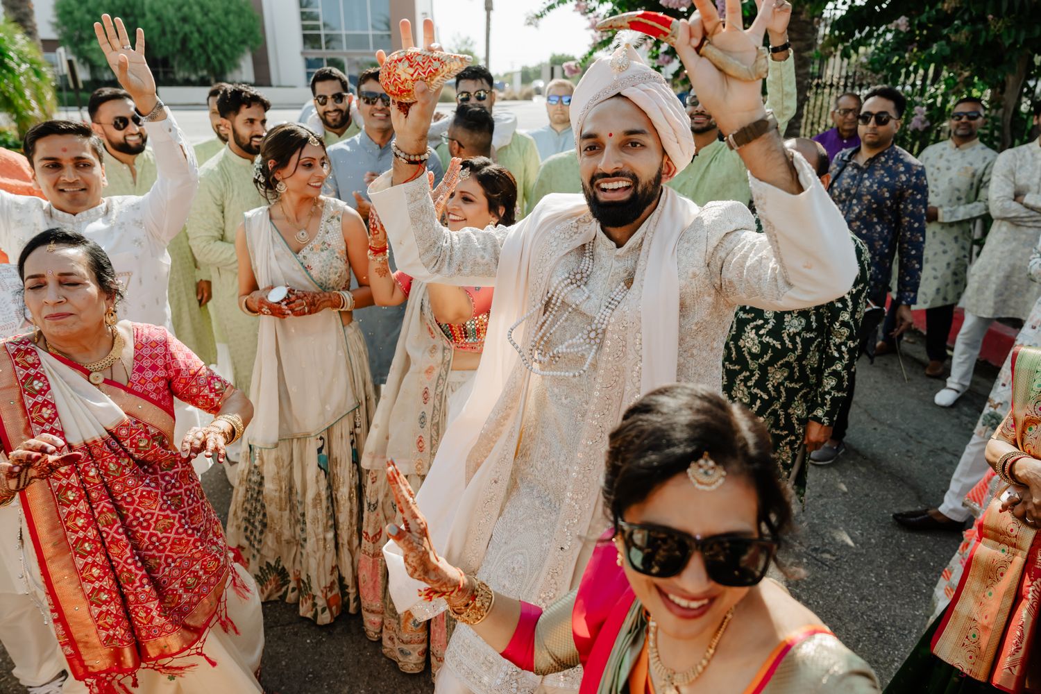 Wedding guests celebrating with raised hands and joyful expressions at an outdoor celebration.
