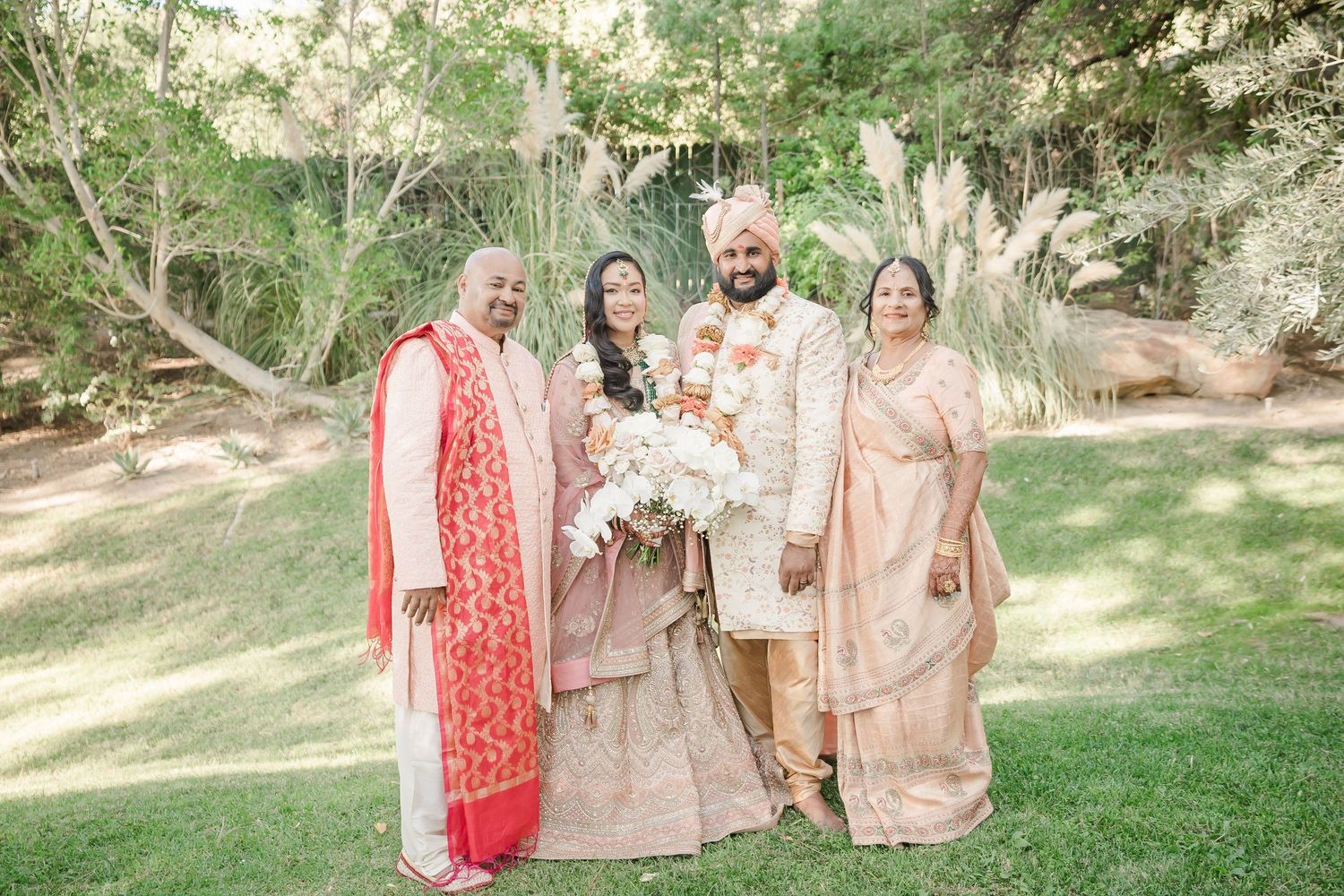 Wedding party members in coordinated peach and coral outfits walking through garden setting.