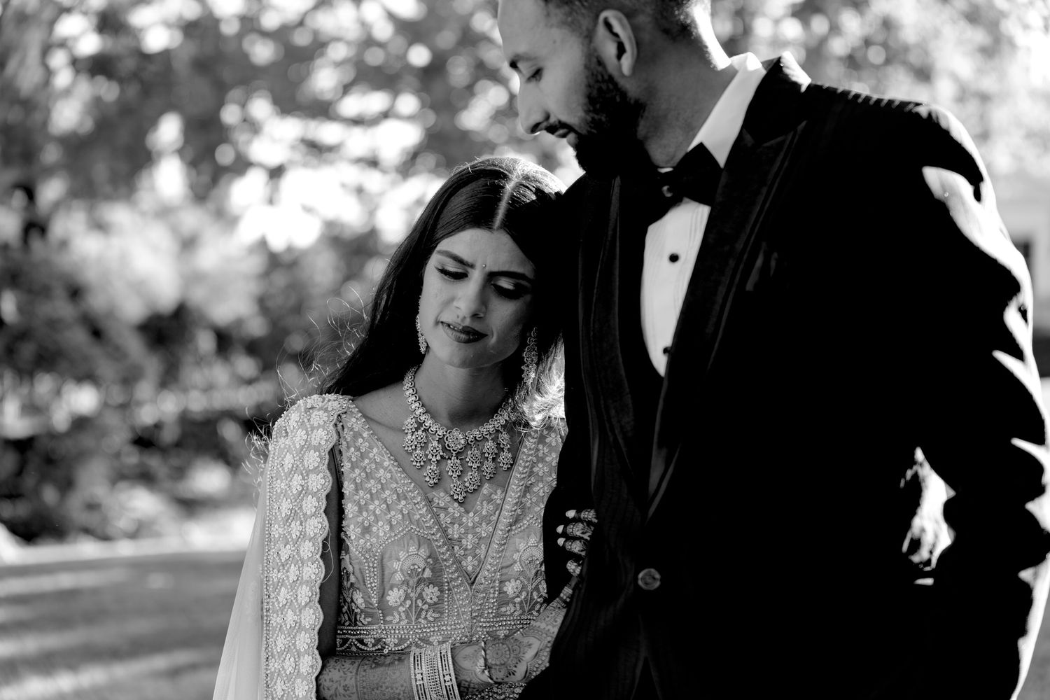 Black and white wedding portrait capturing romantic moment against natural outdoor backdrop.