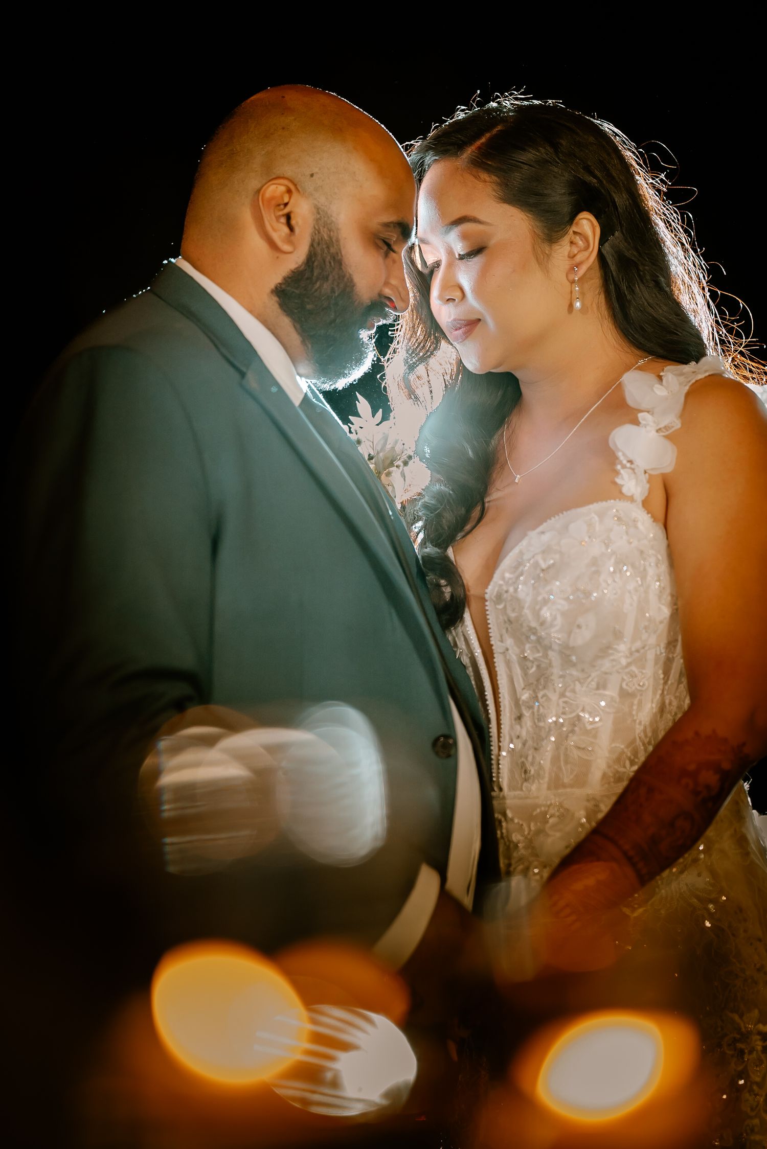 Romantic wedding portrait with soft lighting and lens flares creating an intimate atmosphere between newlyweds.