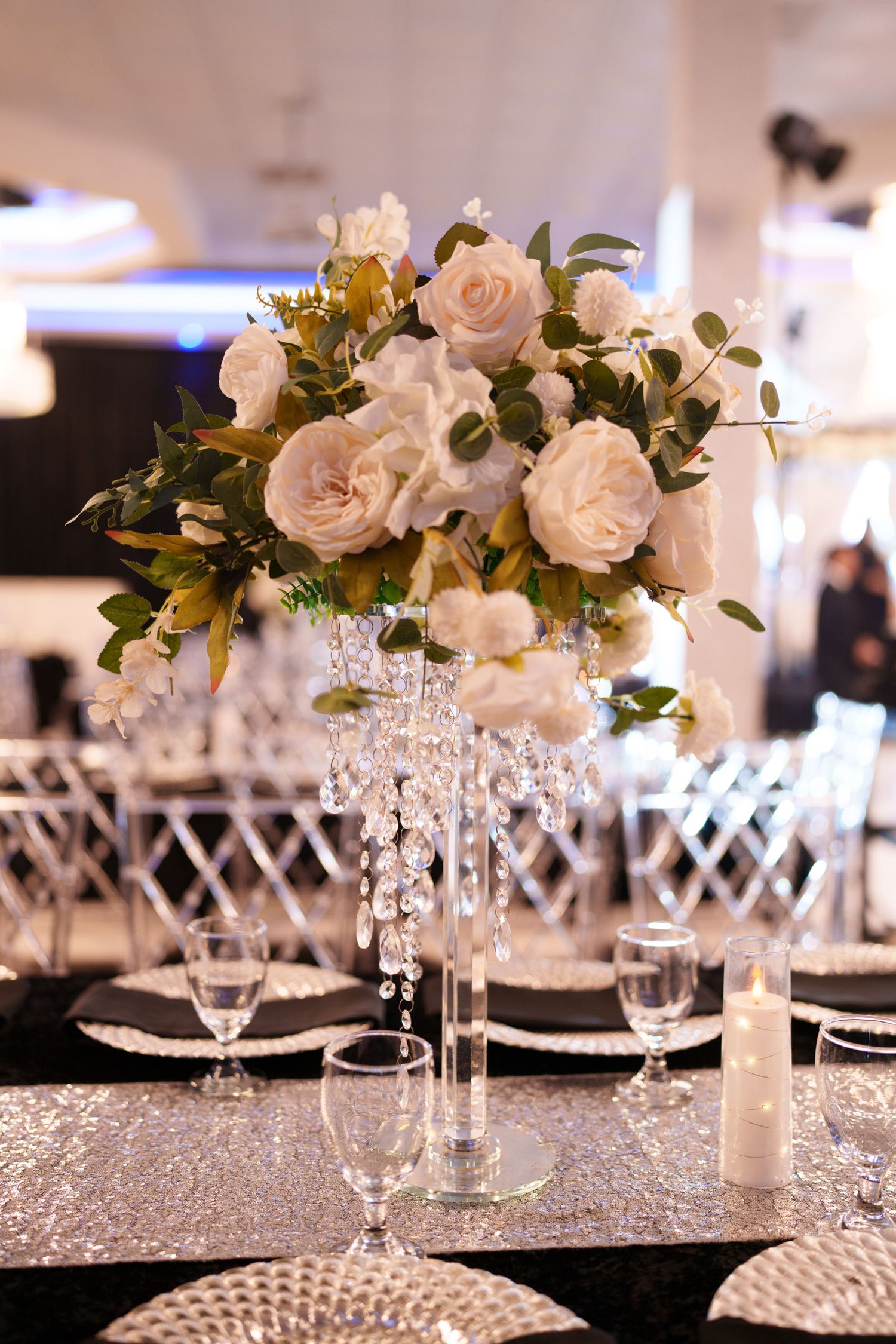 Elegant wedding reception table setting with white roses, crystal candelabras and silver sequin tablecloths.