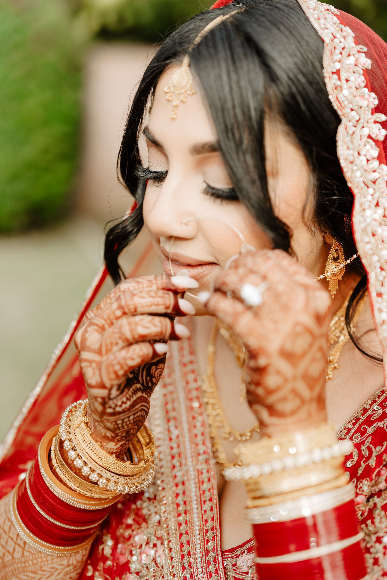 Traditional Indian bridal details showing intricate henna designs and gold bangles with a red dupatta.