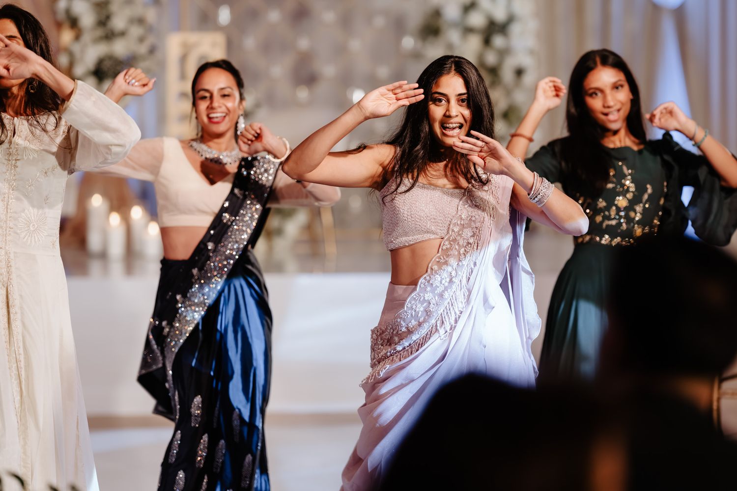 Guests dancing and celebrating at an elegant indoor wedding reception with soft lighting and decorative elements.