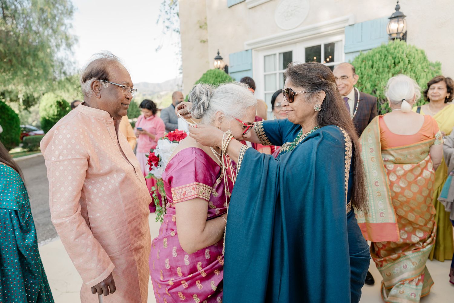 Guests mingling at an outdoor wedding reception wearing colorful traditional attire.