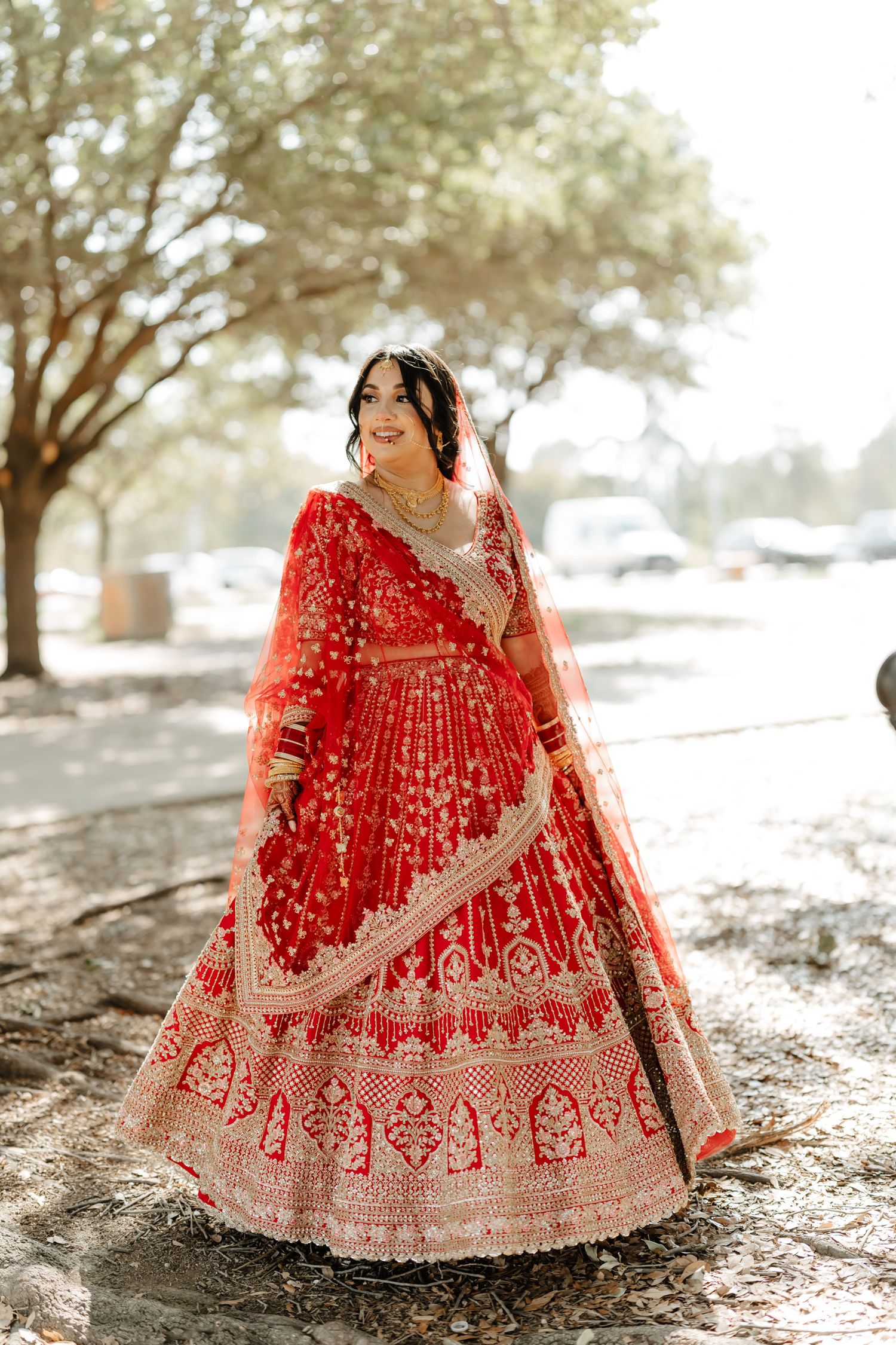 Beautiful red and gold traditional Indian lehenga dress displayed outdoors in natural sunlight.