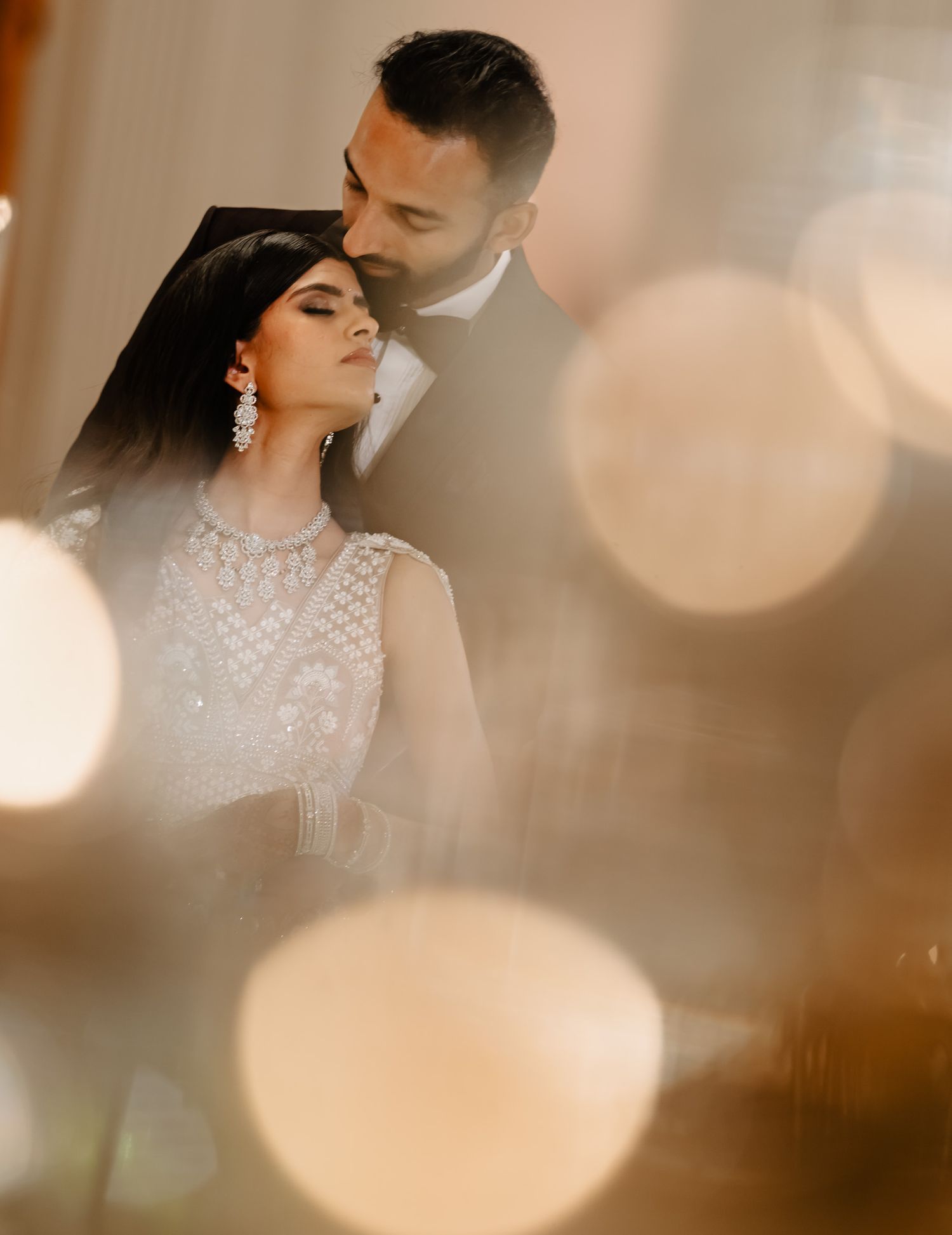 A romantic wedding portrait with soft bokeh lights and elegant white lace attire.