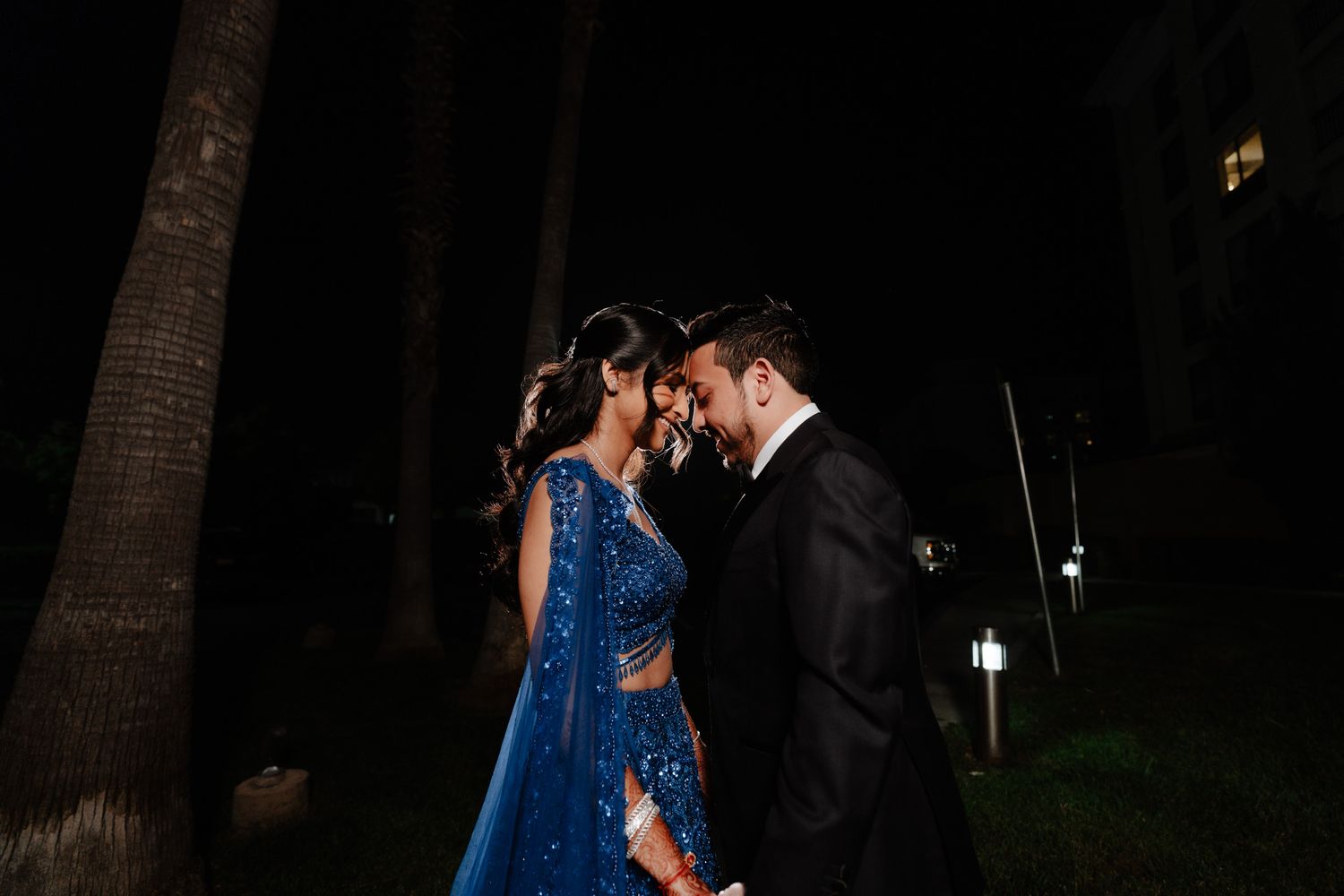Romantic evening dance scene with sparkling blue gown under outdoor lighting.