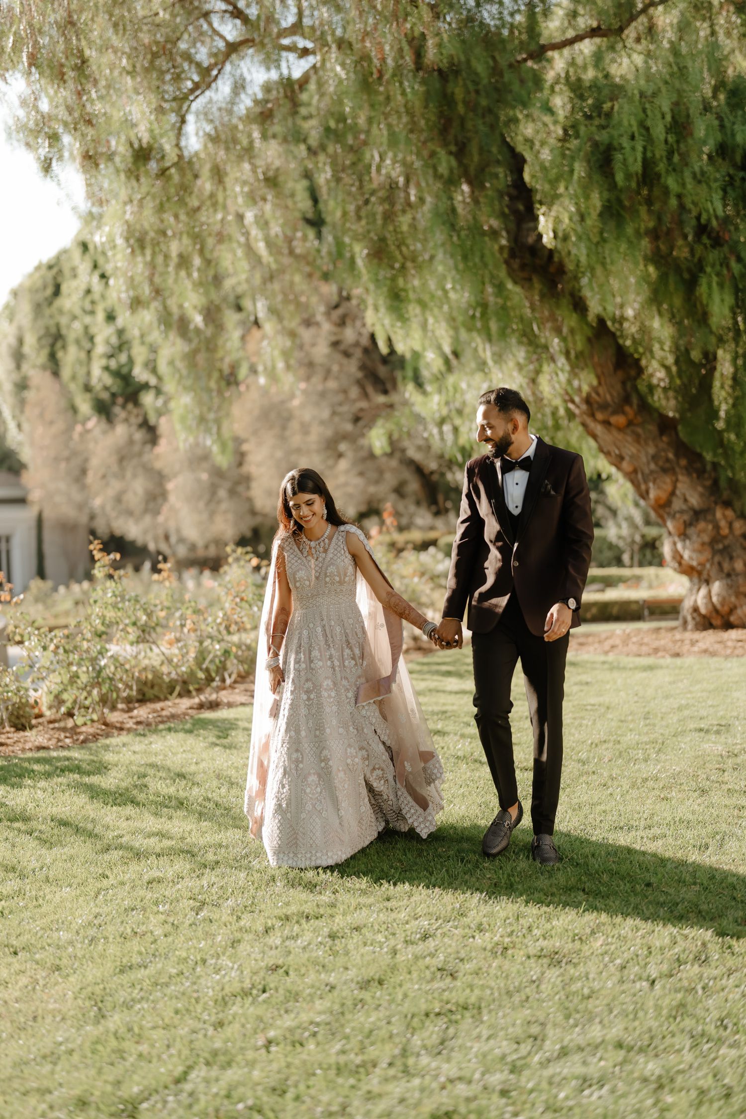 Romantic outdoor photo session under weeping willow trees on grassy lawn.