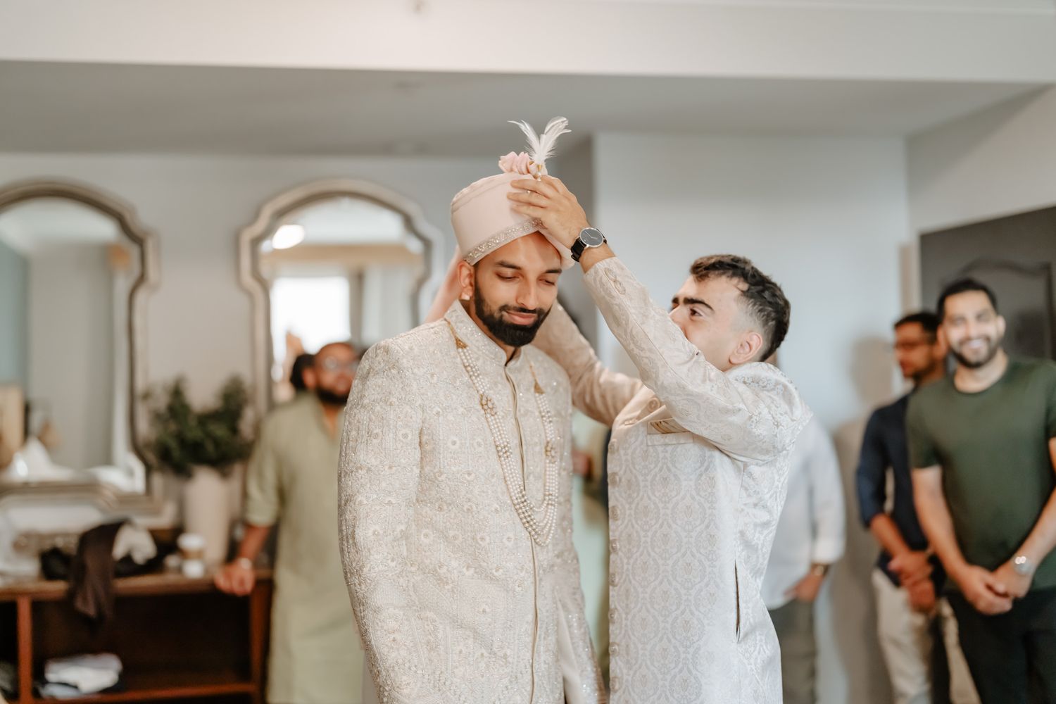 Wedding preparation scene in an elegant room with white decor and arched mirrors.
