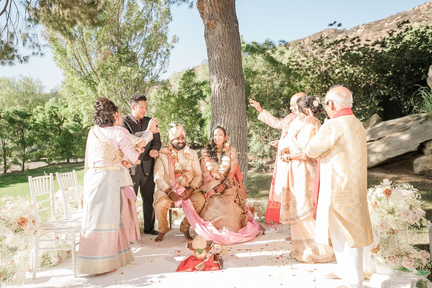 Wedding guests enjoy a festive outdoor celebration with string lights and trees in a garden setting.