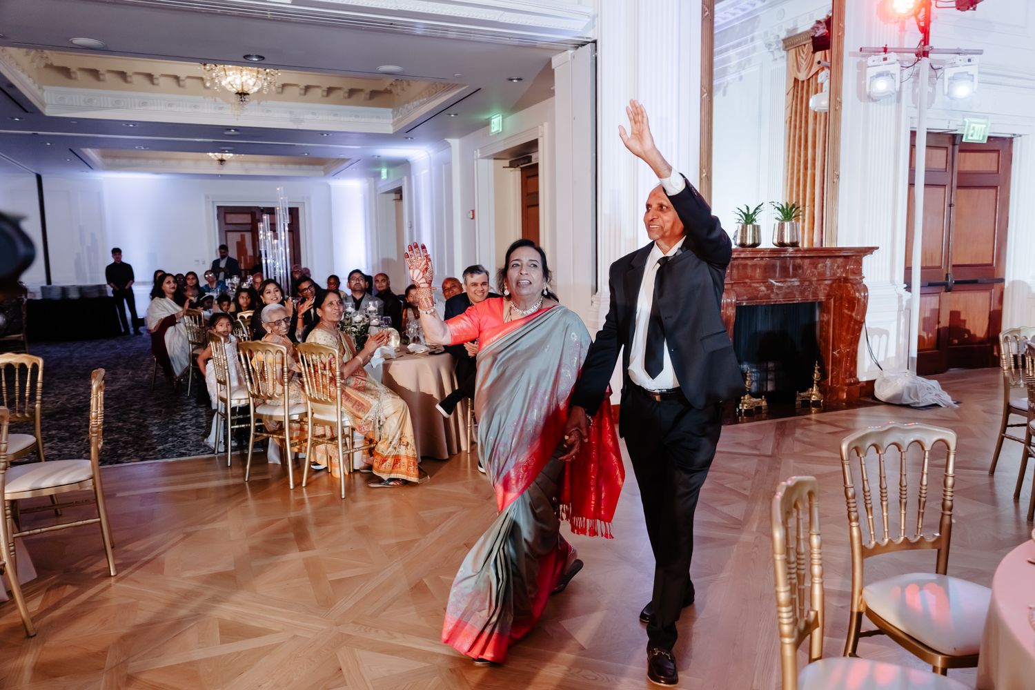 Wedding guests celebrating on dance floor at elegant indoor reception venue.
