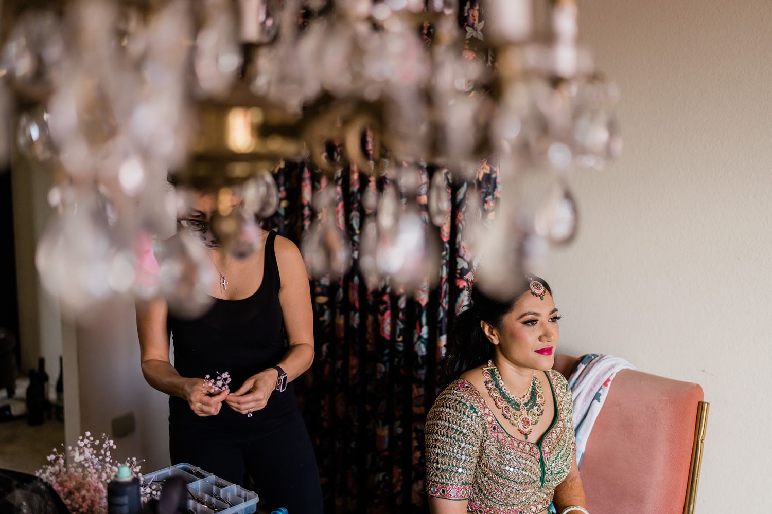 Wedding party getting ready in an elegant room with crystal chandeliers and soft lighting.
