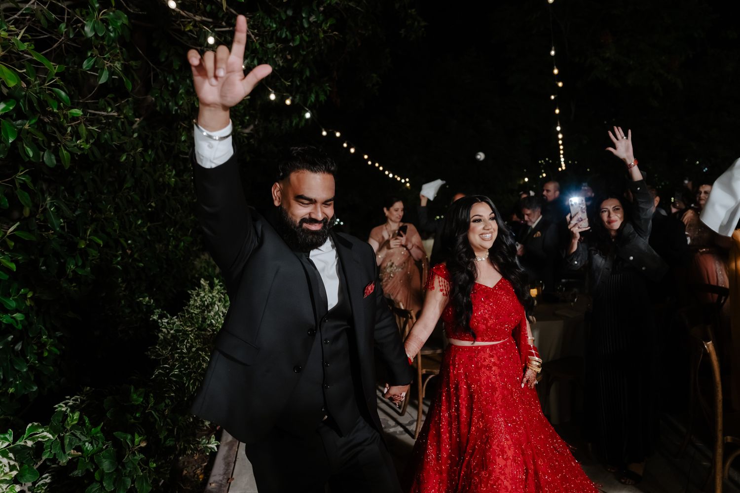 Wedding celebration at night with string lights as guests dance and celebrate.