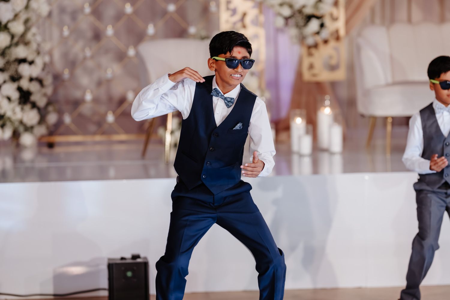Wedding guests dancing and celebrating on an elegant white dance floor with floral decorations.