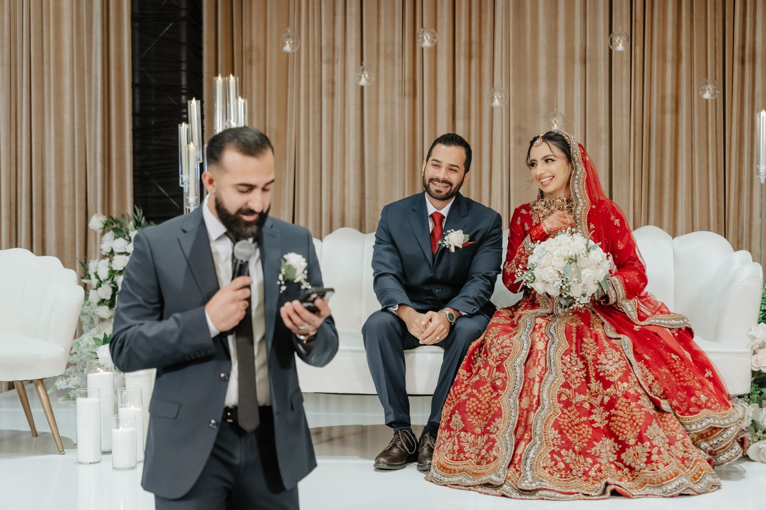 Traditional South Asian wedding ceremony with decorative backdrop and ornate red attire.