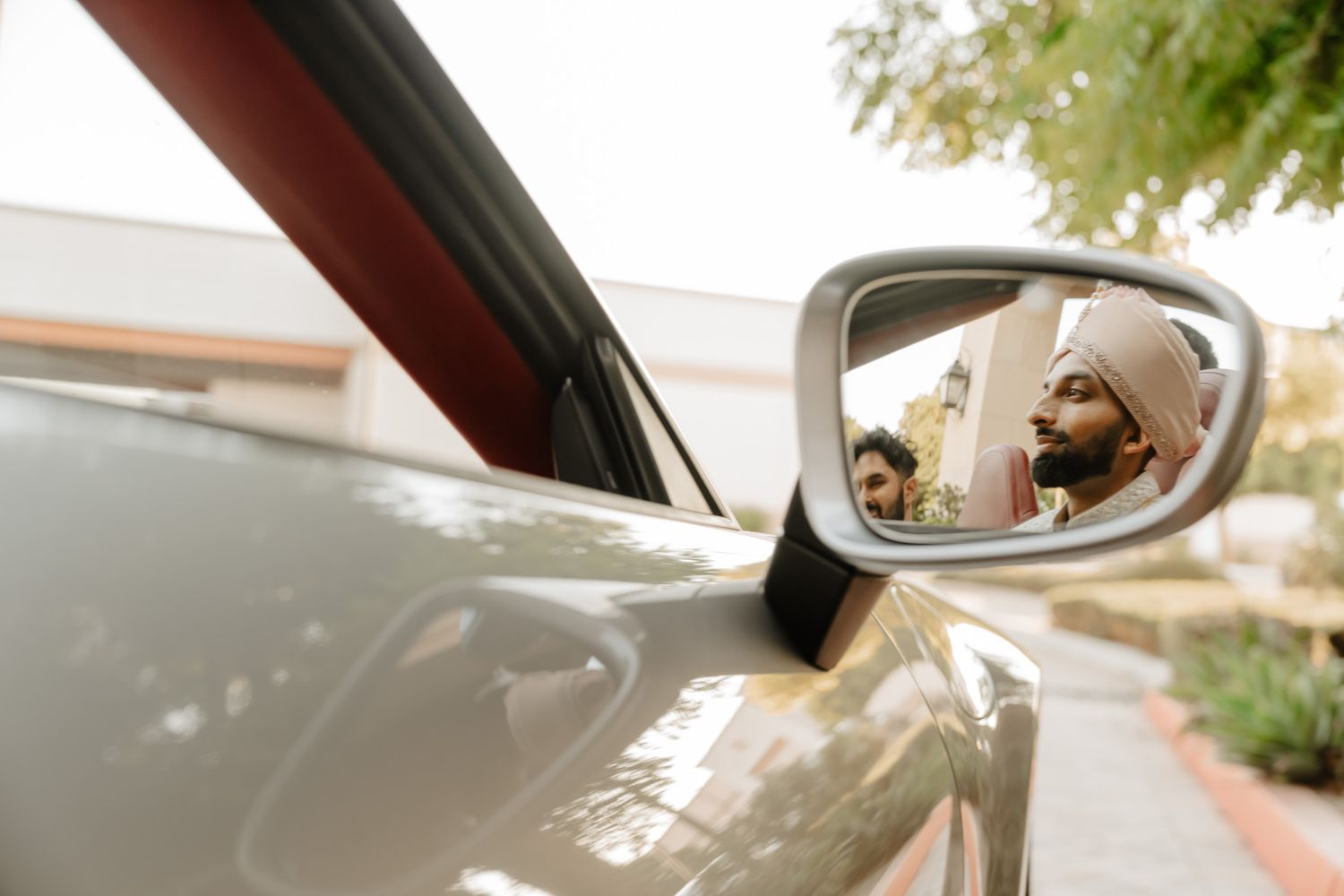 Side mirror reflection shows a temple building with intricate architectural details in warm sunlight.