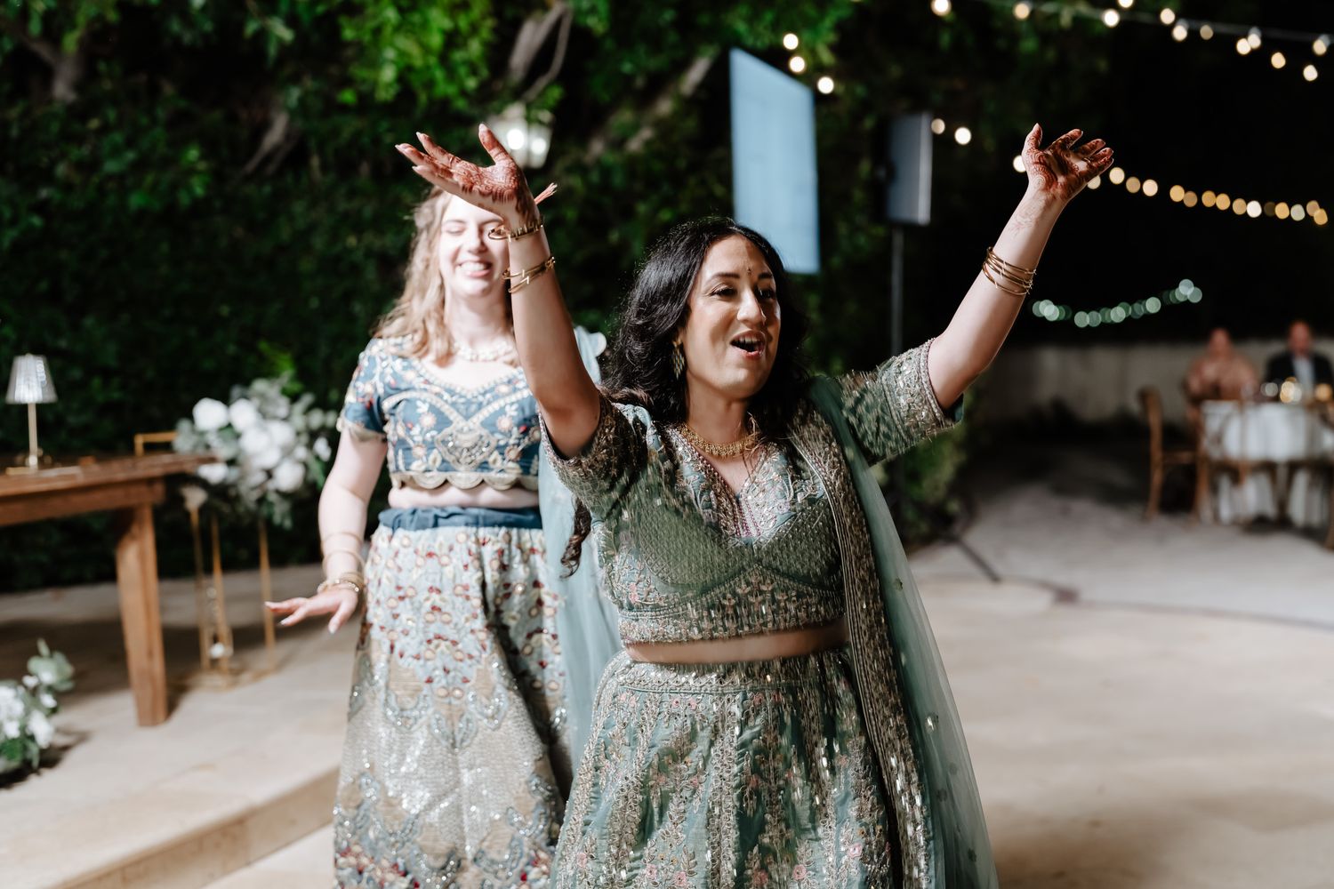 Wedding party celebrates in an outdoor venue decorated with twinkling string lights.