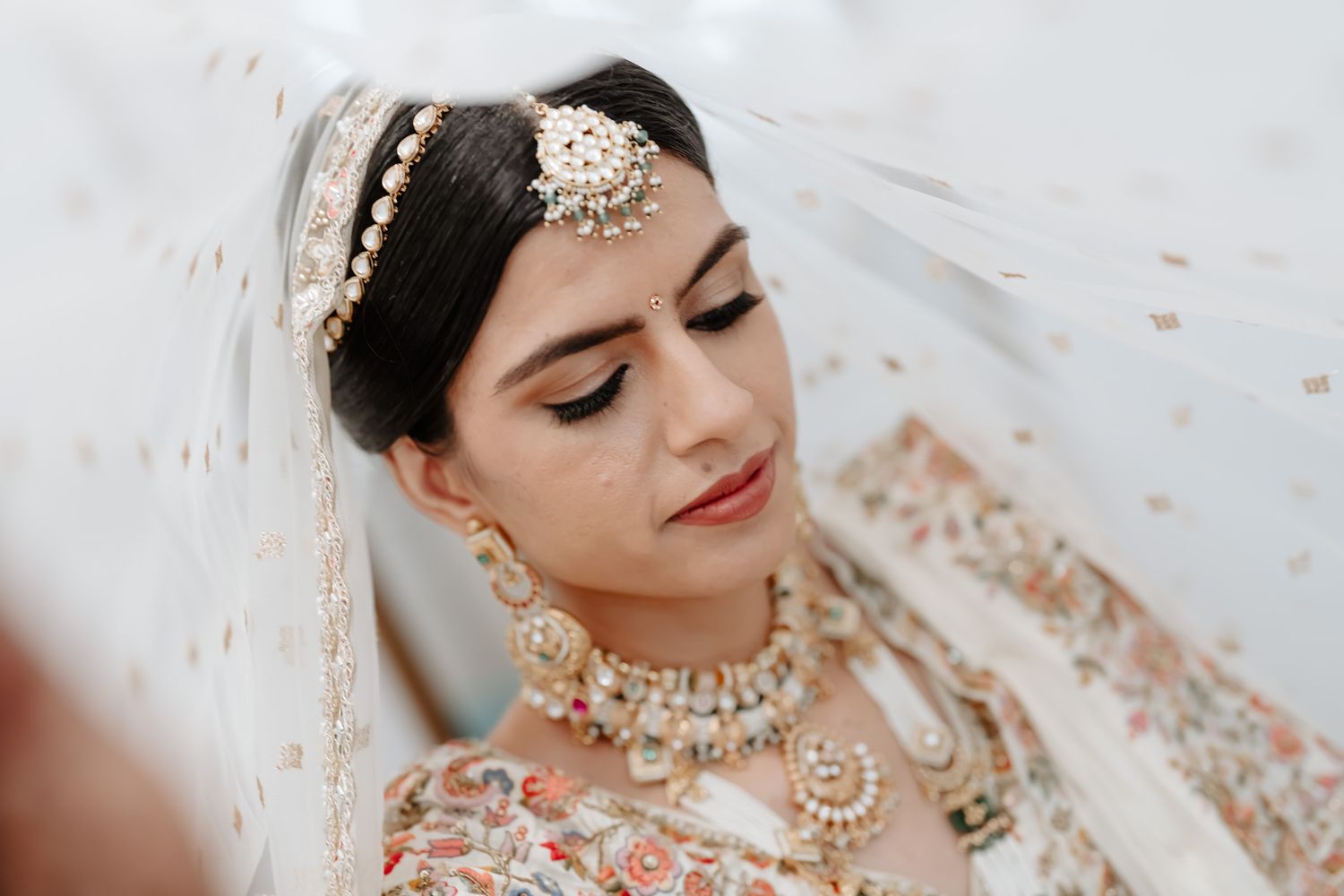 Close-up of traditional Indian bridal jewelry and makeup details with intricate headpiece.
