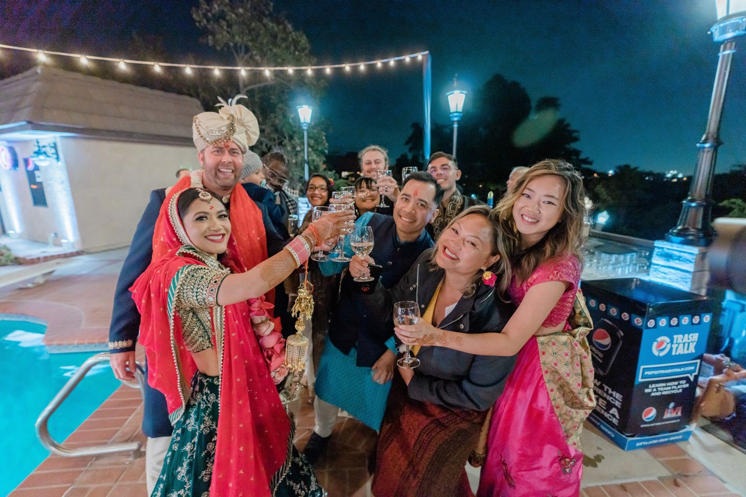 People dancing and celebrating at an outdoor evening event with string lights overhead and festive atmosphere.