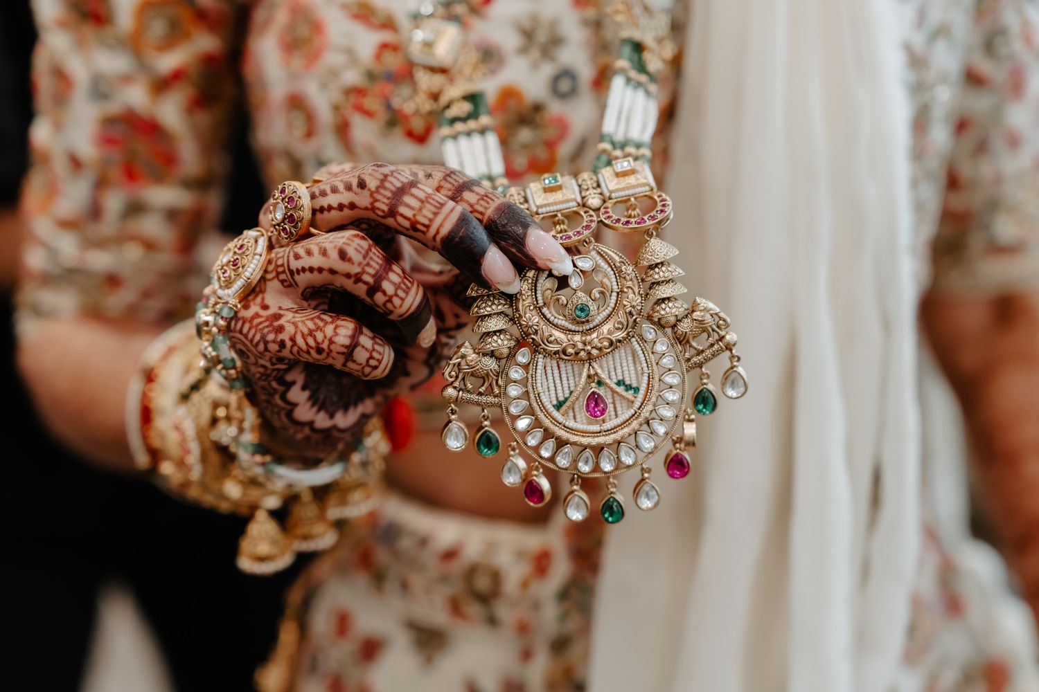 Ornate Indian bridal jewelry with intricate gold designs and colorful gemstones displayed on hands.