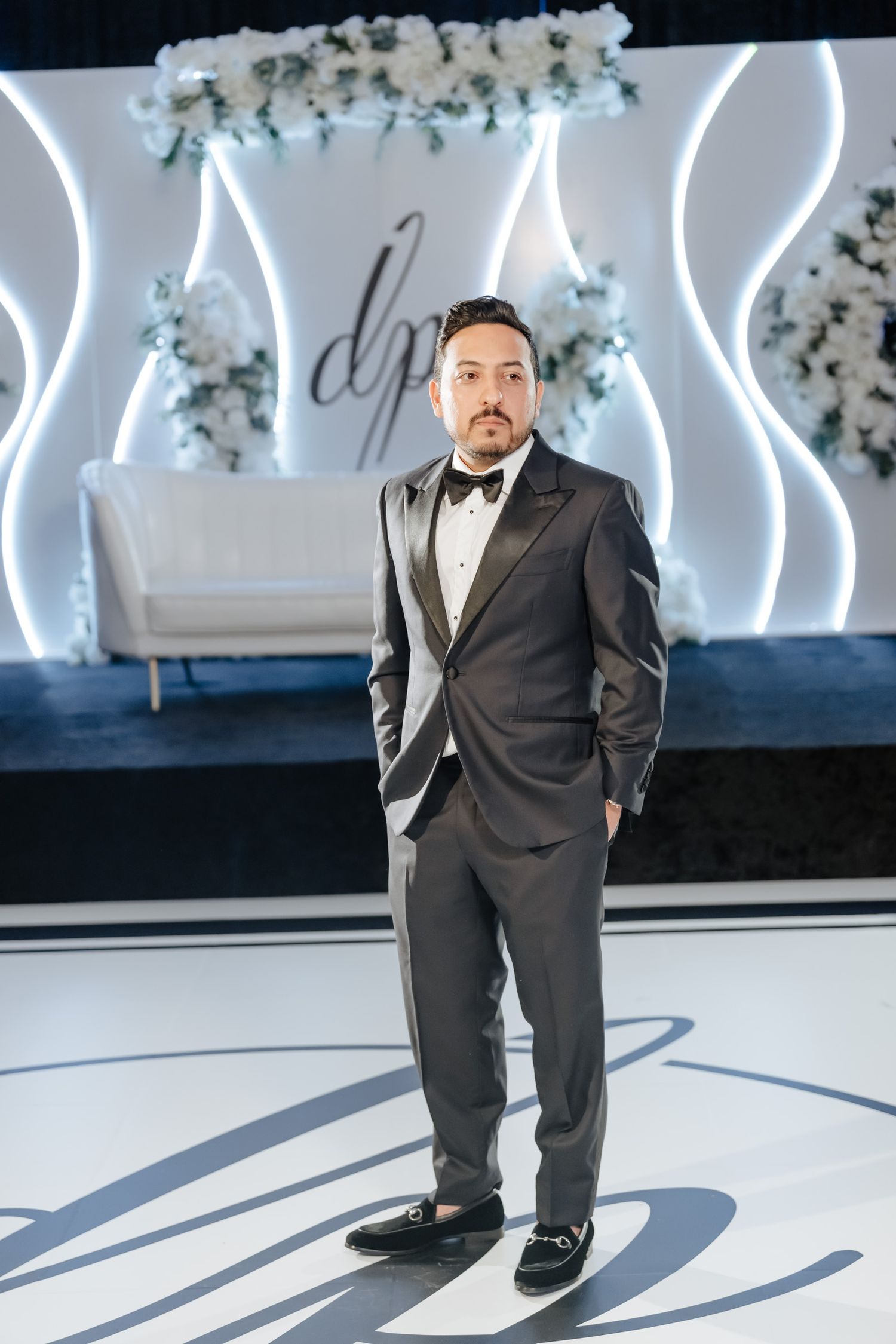 Modern wedding venue with illuminated white wavy wall decorations and floral accents.